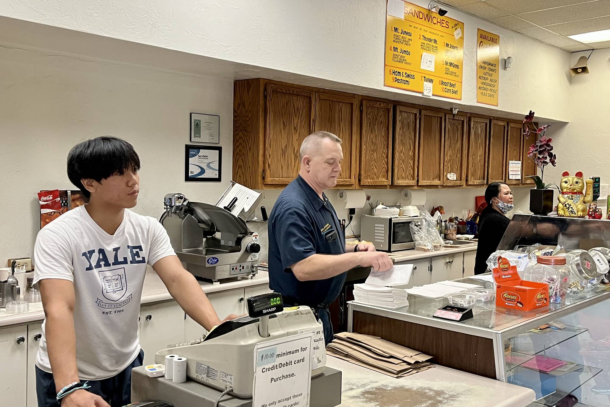 It was business as usual for the Doogan family, Isaac, Neil and Alma, as they steadily work through a busy lunch rush Tuesday at J&J Deli and Asian Market. (Jonson Kuhn / Juneau Empire)