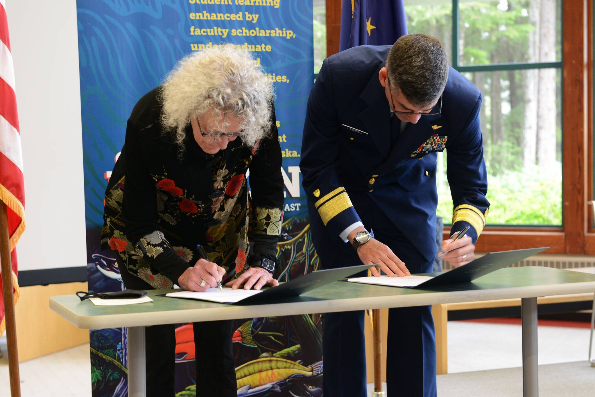 University of Alaska Southeast chancellor Karen Carey, left, and Rear Adm. Nathan Moore, commander of Coast Guard District 17, sign a memorandum of agreement for renewal of the College Student Pre-Commissioning Initiative at the college on July 25, 2022. (Courtesy photo / USCG)