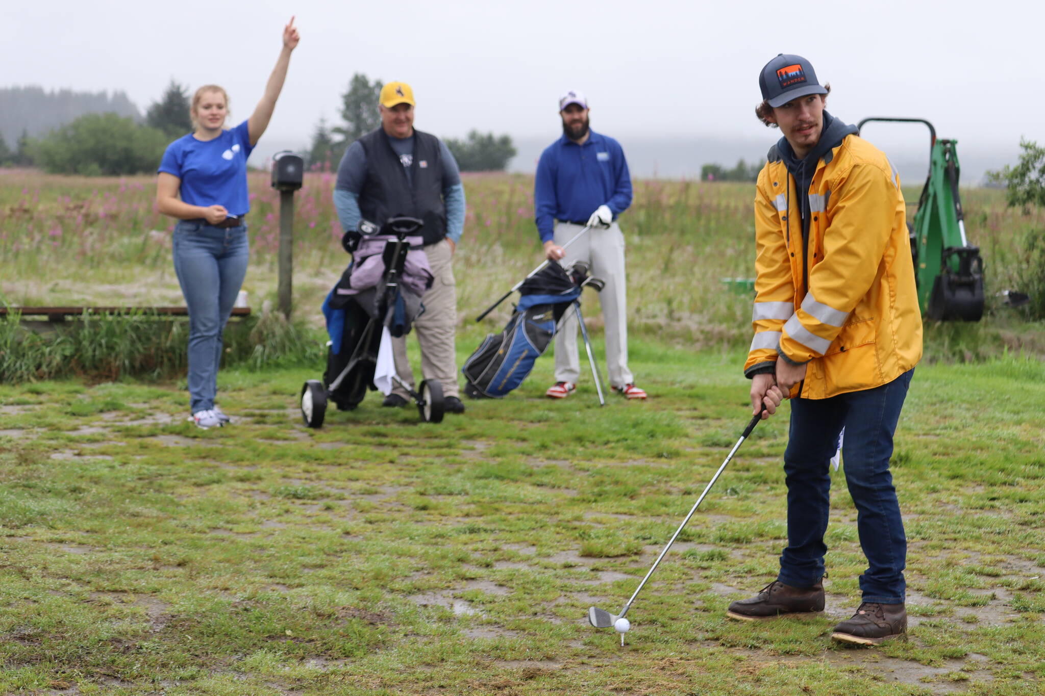 John Cashell prepared to tee off in the rain while the rest of his team, Haley Snell, Marty Stearns, and Josh Pritts, cheered on quietly from behind. (Jonson Kuhn / Juneau Empire)