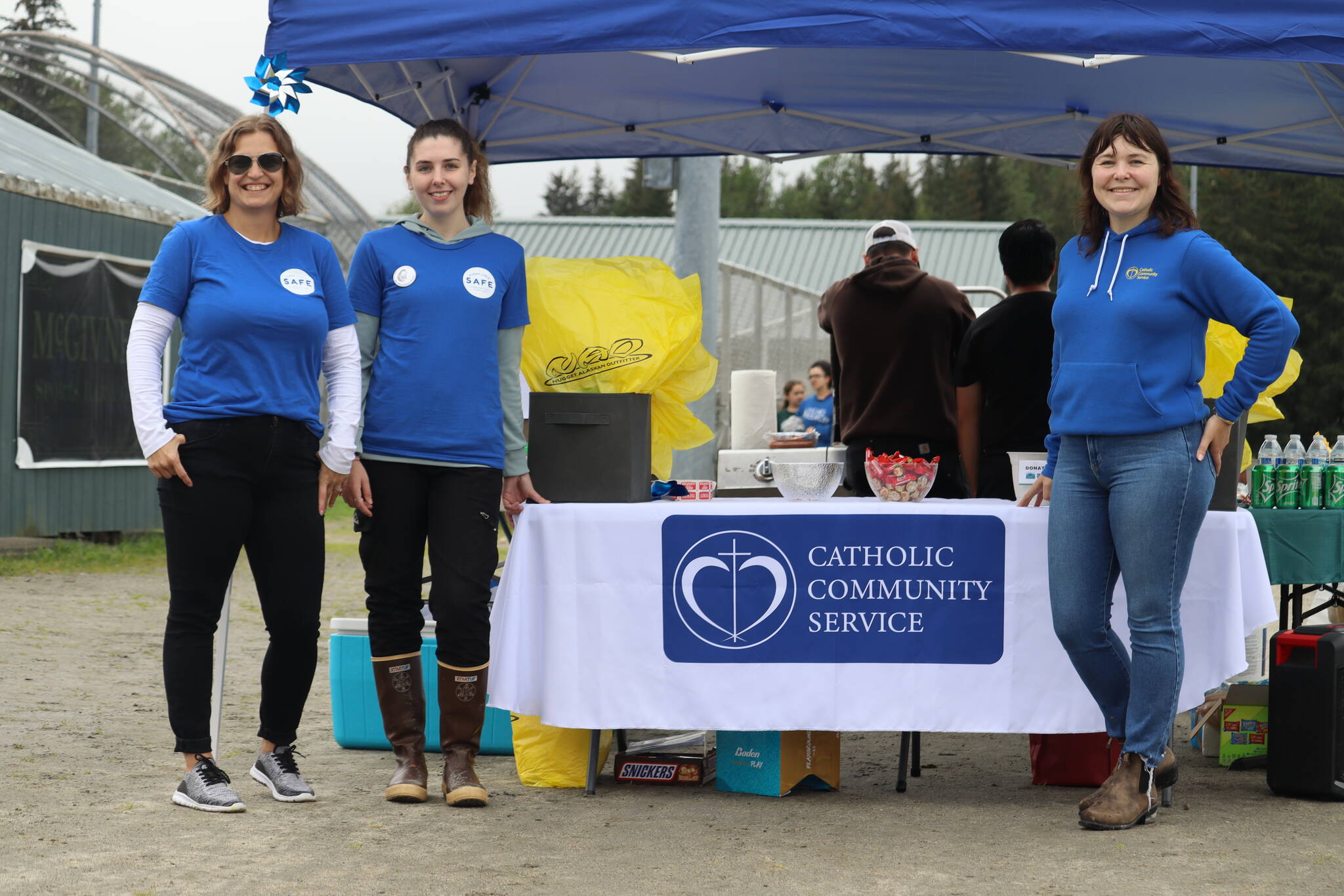 Rikki DuBois, Claire Norman and Erin Youngstrom stand at the Catholic Community Service booth on Saturday for SAFE Child Advocacy Center’s first Family Day at the Park at the Dimond Park Field House. (Jonson Kuhn / Juneau Empire)