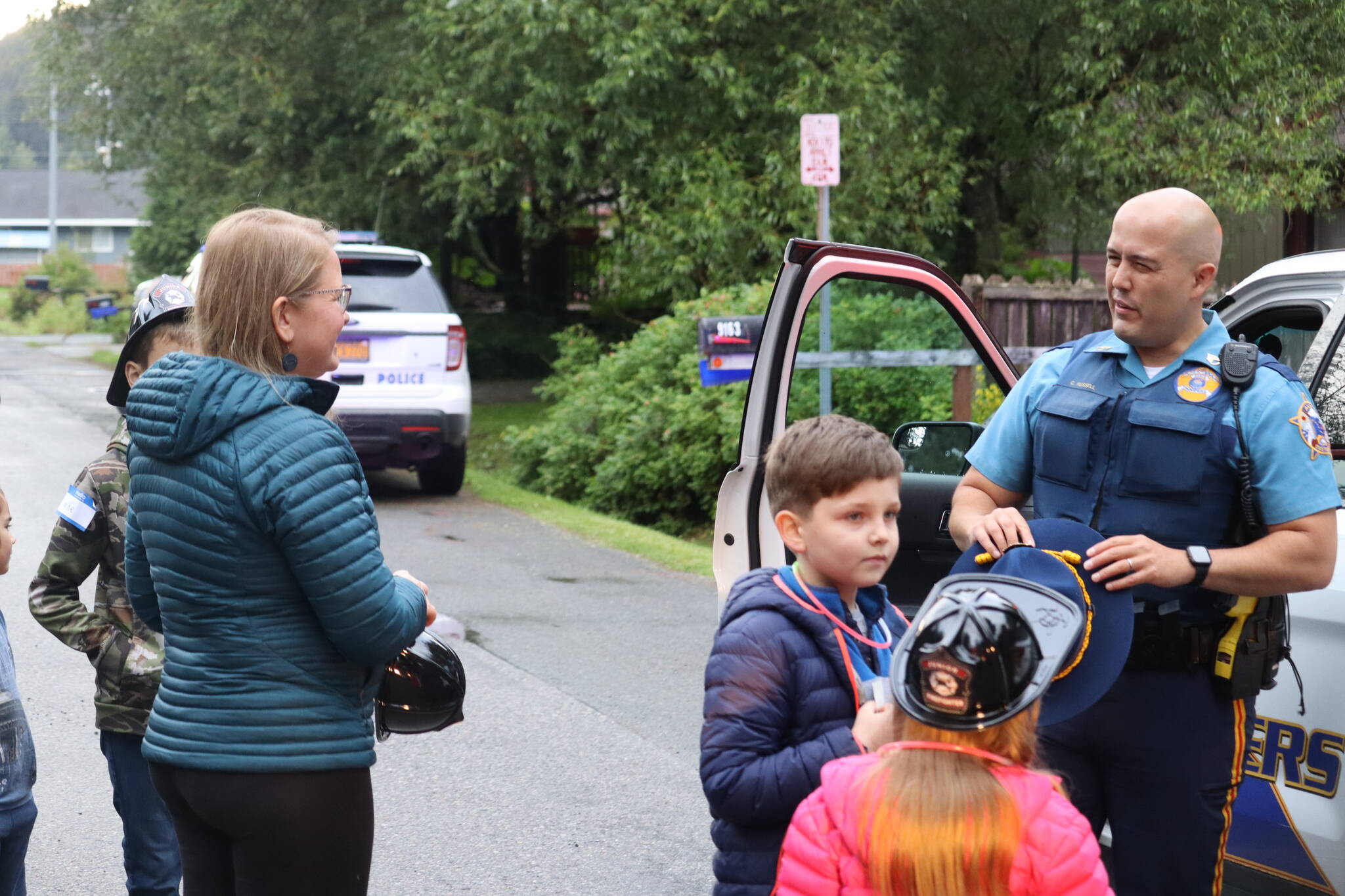 Alaska State Trooper Sgt. Chris Russell spoke with Valentina Gouk and others from the Skywood Lane neighborhood while the kids got a chance to interact with his squad car. (Jonson Kuhn / Juneau Empire)