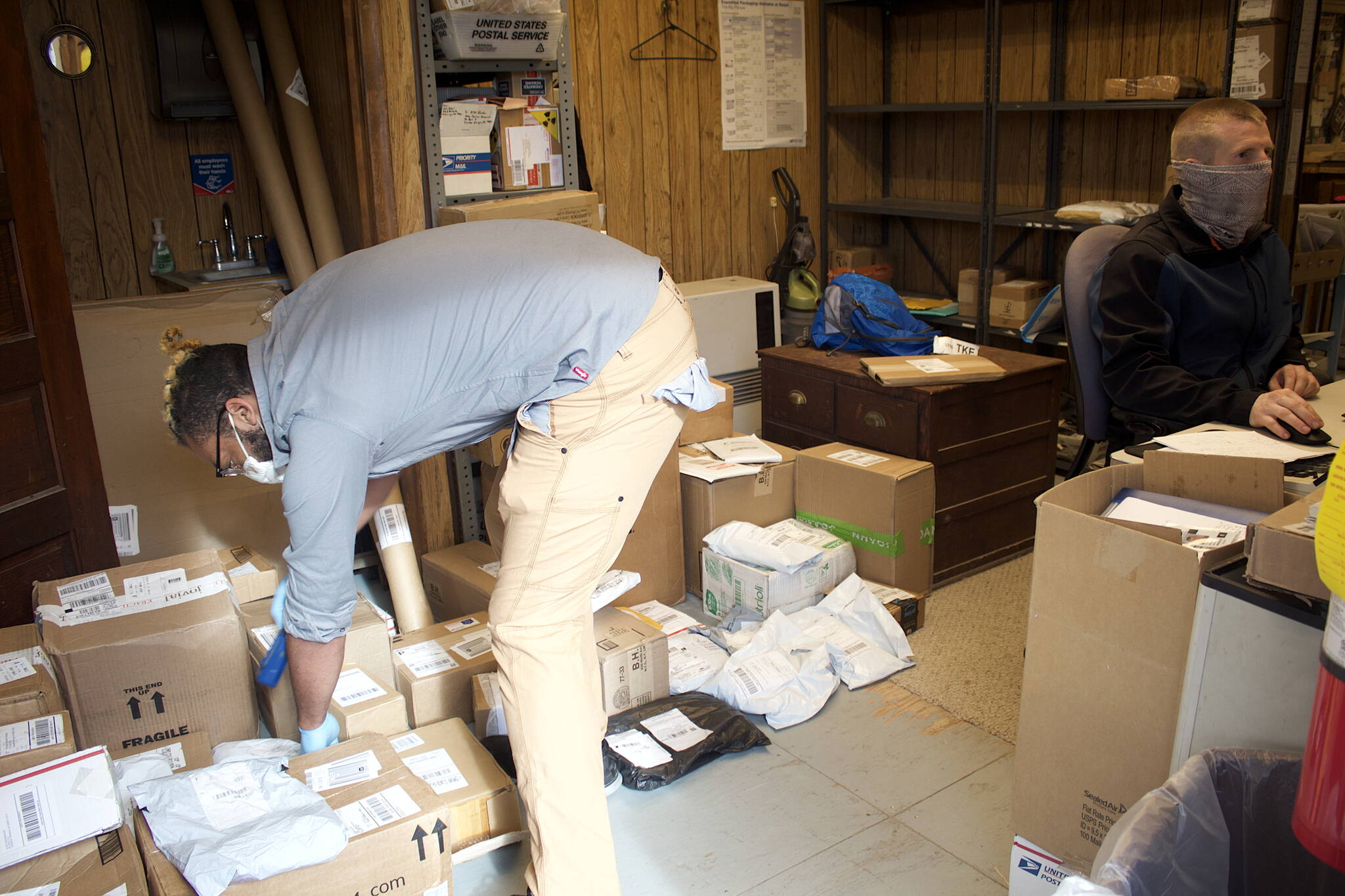 J.T. Collins, left, and Flint Allred sort through the backlog of mail at the Tenakee Springs post office that accumulated as of Monday morning when the post office was closed for more than a week due to their absence and the departure of a third employee at the post office. (Mark Sabbatini / Juneau Empire)