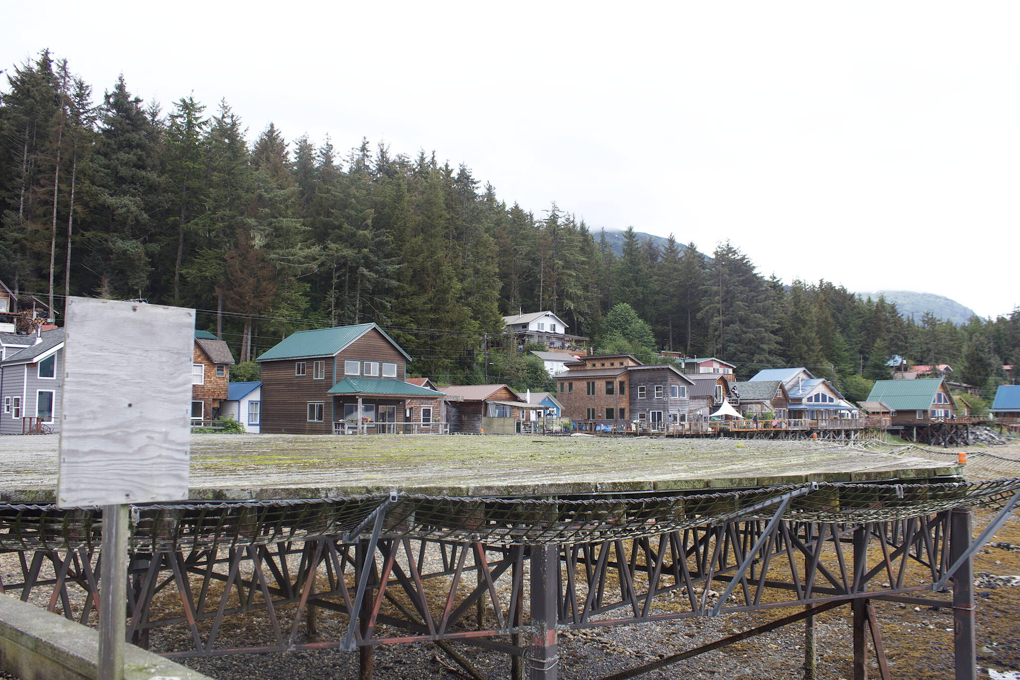 A blank wood sign at the seaplane dock welcomes people to Tenakee Springs, where the adjacent moss-covered helipad has been in disrepair and unusable for years. The town is struggling with numerous infrastructure deficiencies, along with a shrinking population and uncertain future. (Mark Sabbatini / Juneau Empire)