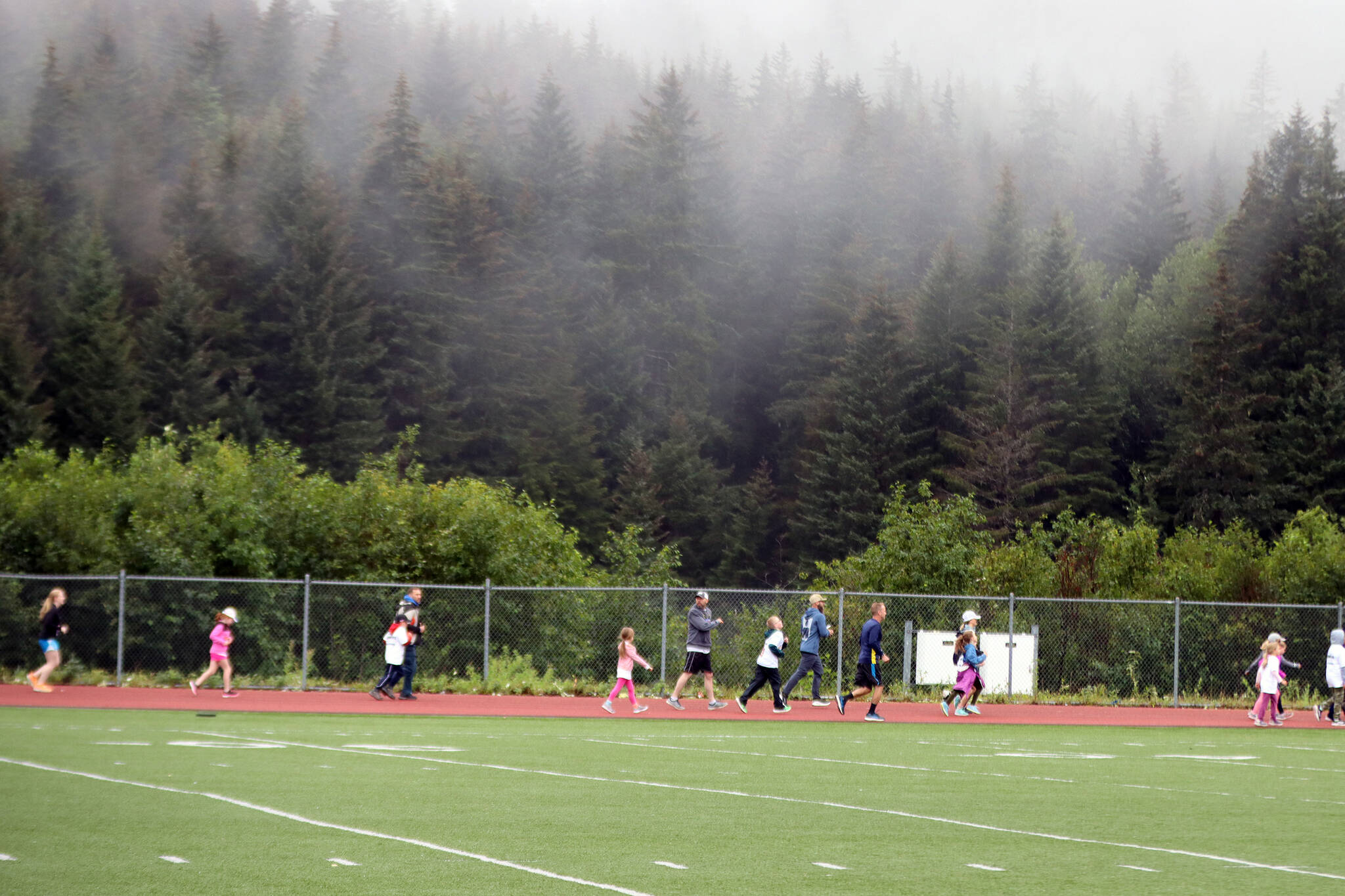 Fun runners on Saturday make their way around the Thunder Mountain High School track during a Ironkids Alaska Fun Run event. (Ben Hohenstatt / Juneau Empire)