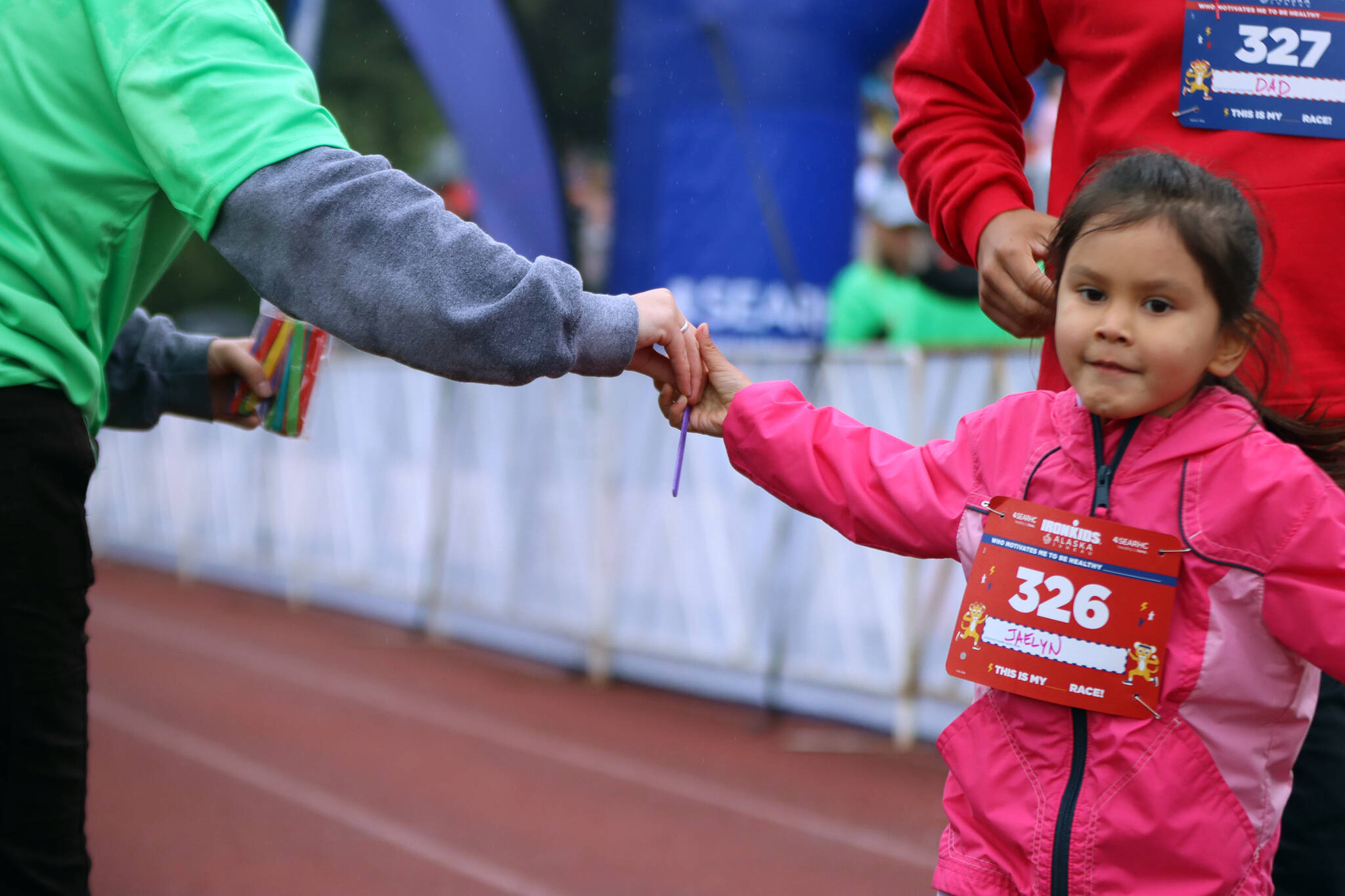 Jaelyn Jackson, 4, takes a Popsicle stick in stride Saturday at Thunder Mountain High School for the Ironkids Alaska event. The sticks allowed volunteers to keep track of who had completed their first lap around the track. (Ben Hohenstatt / Juneau Empire)