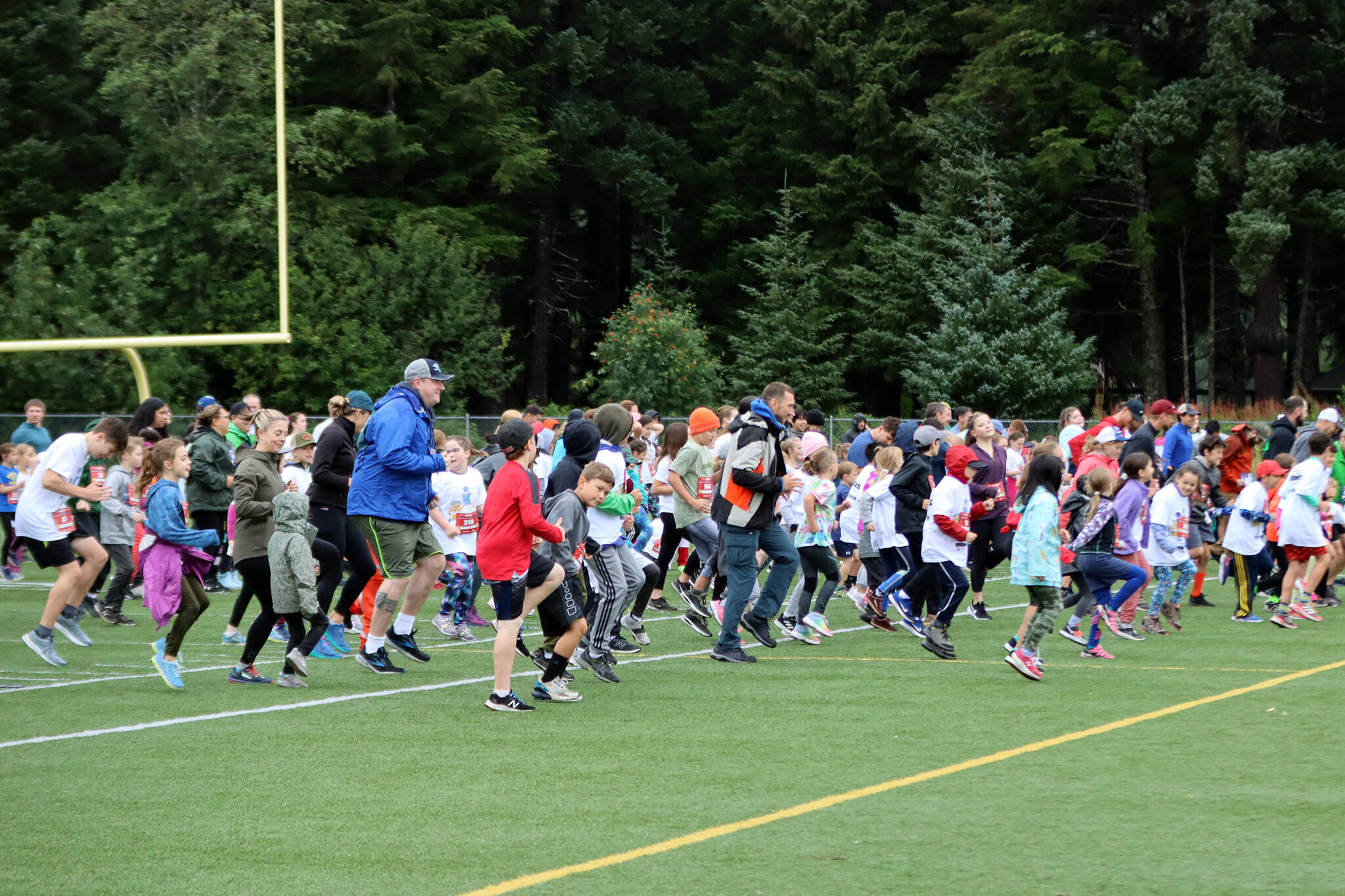 Adults and children take to the field at Thunder Mountain High School to warm up before an Ironkids Fun Run. (Ben Hohenstatt / Juneau Empire)