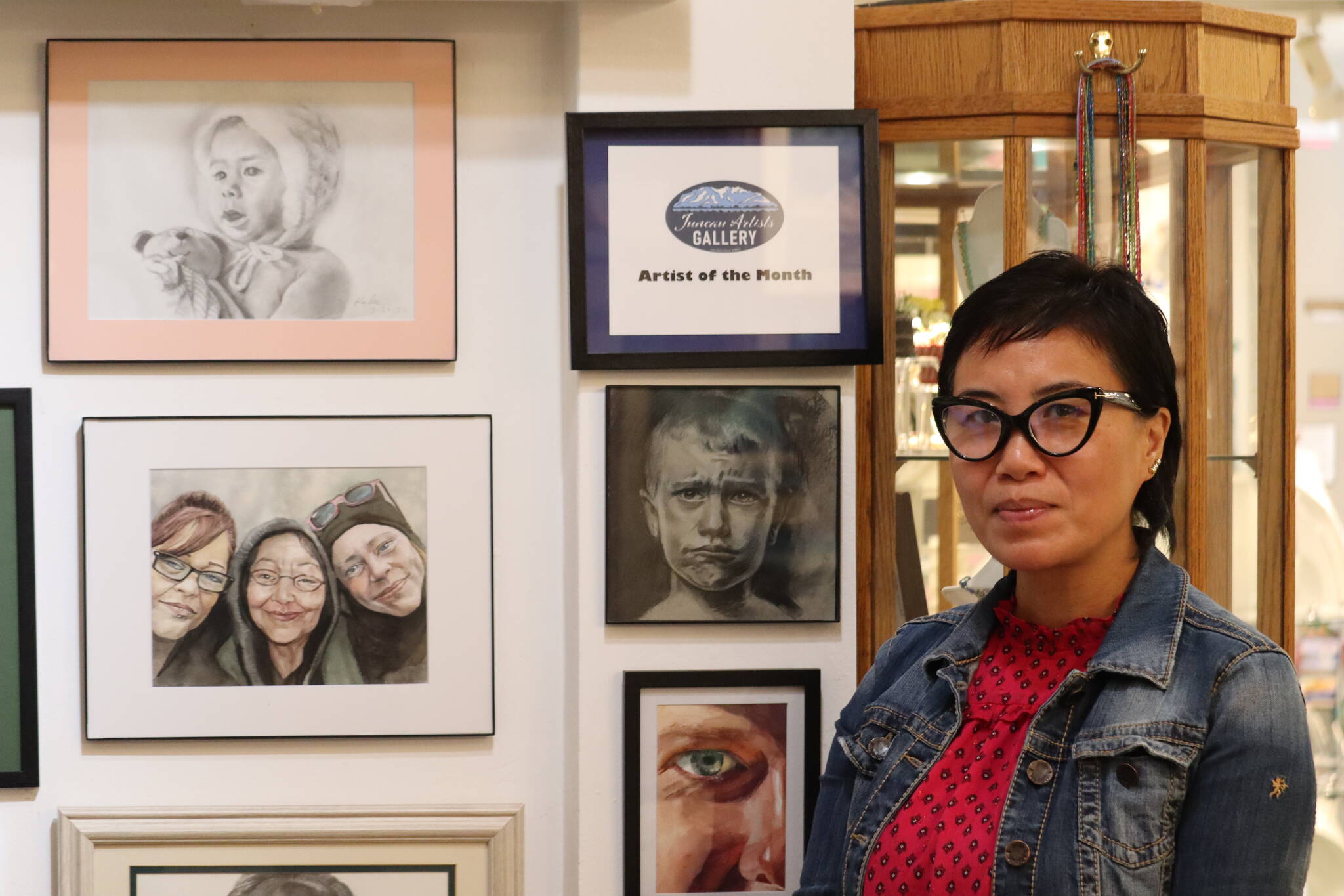 Keke Tian Ke featured in this photo on First Friday next to her work which is on display at the Juneau Artist Gallery located at 175 S. Franklin St. Ke is the gallery’s artist of the month. (Jonson Kuhn / Juneau Empire)