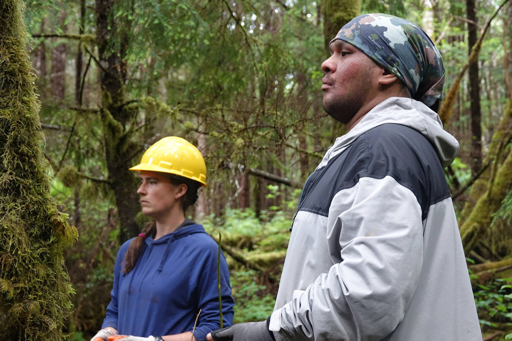 From left, Kelsey Dean, watershed scientist with the Southeast Alaska Watershed Coalition, and Kaagwaan Eesh Manuel Rose-Bell of Keex’ Kwáan watch as crew members set up tools to drag a log into place. Healthy salmon habitat requires woody debris, typically provided by falling branches and trees, which helps create deep salmon pools and varied stream structure. (Courtesy Photos / Mary Catharine Martin)