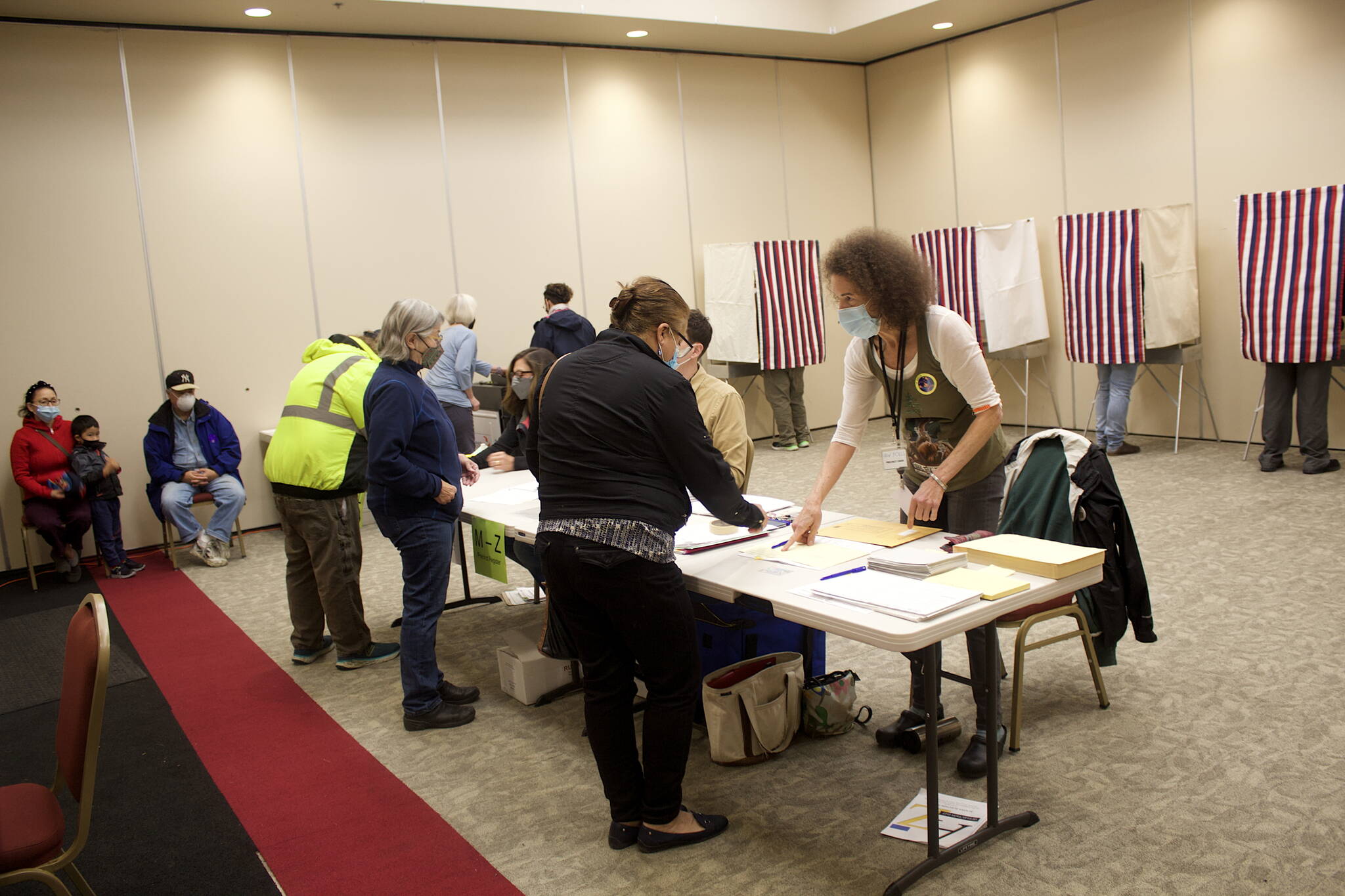 Emily Kane, precinct chair at the Elizabeth Peratrovich Hall polling station, instructs a voter on filling out the ballot for Tuesday’s combined special and primary election. Kane, a local election worker since 2016, said there is a high rate of spoiled ballots this year due to confusion about the new ranked choice voting system. (Mark Sabbatini / Juneau Empire)