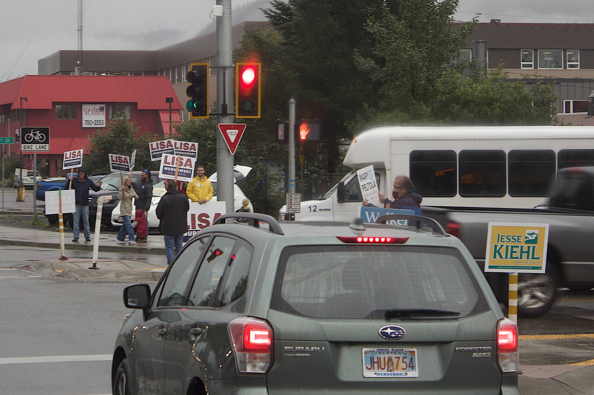 Supporters of candidates from various parties in the races for U.S. House, U.S. Senate, governor and Alaska State Legislature waves signs during rush hour in the rain at the intersection of Egan Drive and 10th St. (Mark Sabbatini / Juneau Empire)