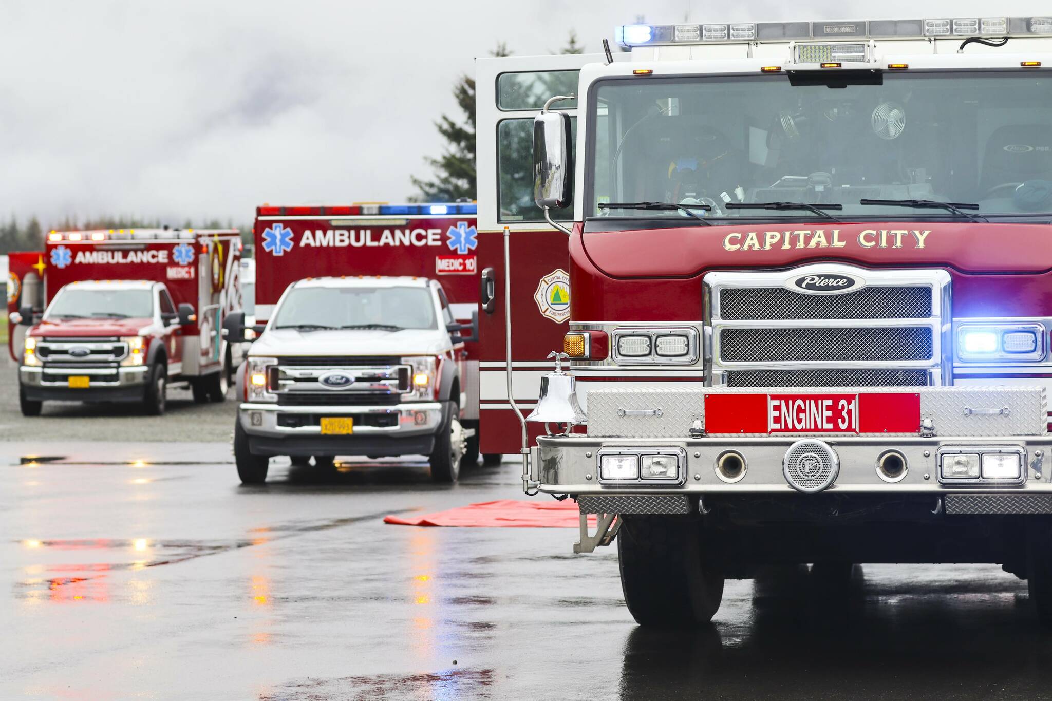 Fire trucks flash their lights in a line during an emergency drill at Juneau International Airport. (Michael S. Lockett / Juneau Empire File)