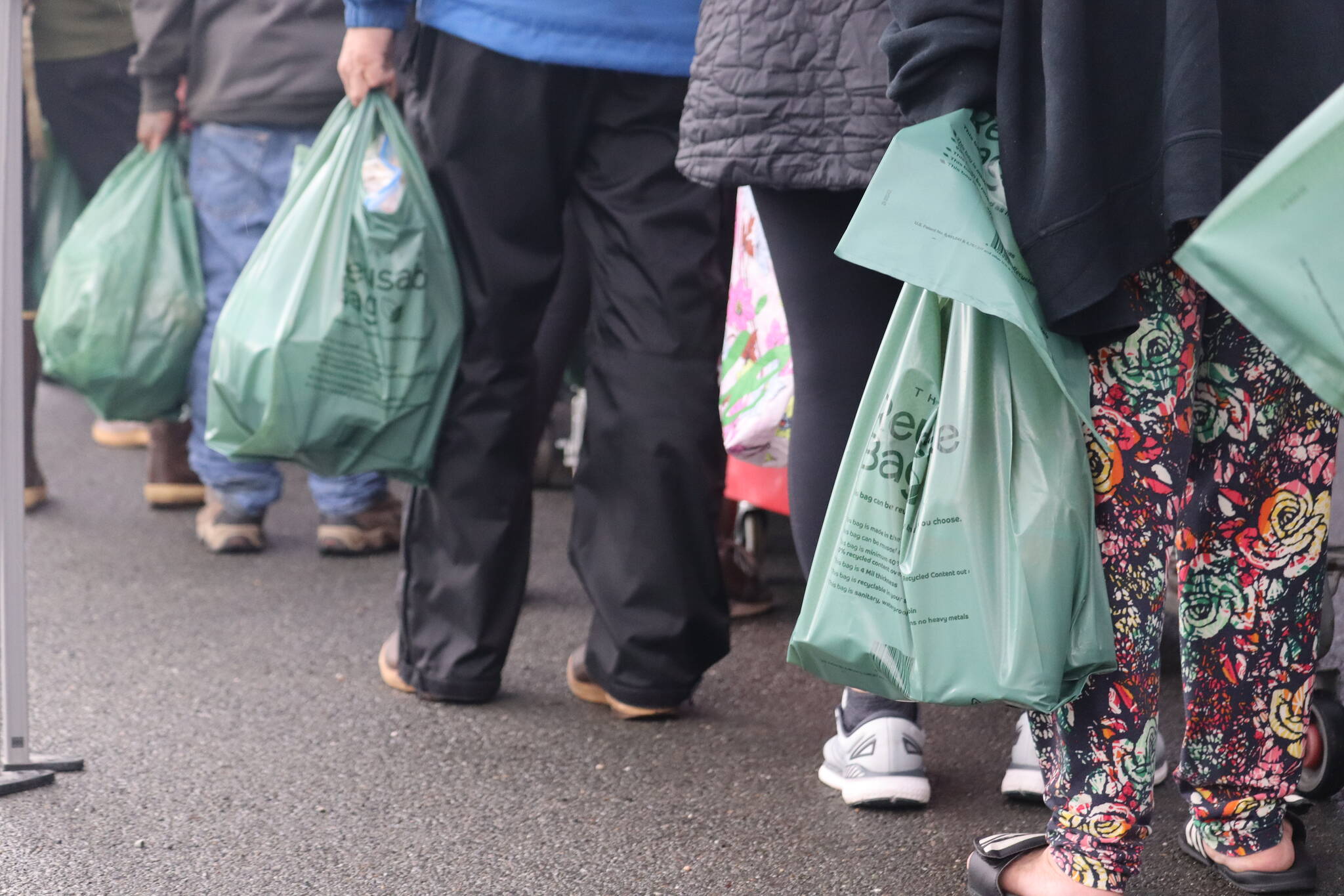 A long line of residents stand with bags in hand, digging through scarce supplies on a rainy Tuesday afternoon in Juneau at the Southeast Alaska Food Bank. (Jonson Kuhn / Juneau Empire)
