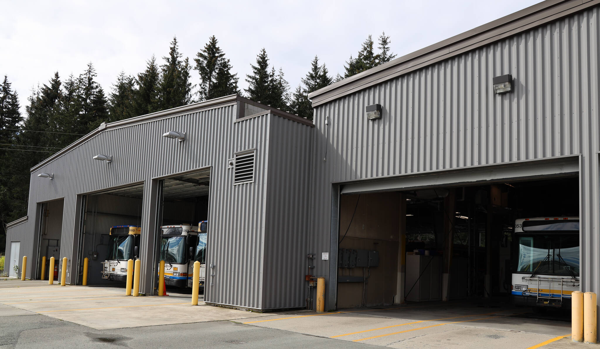 Buses line the open garage doors of the City Borough of Juneau Capital Transit’s bus barn on Tuesday afternoon. Seven new electric buses will replace old diesel burning buses being used by the city. (Clarise Larson / Juneau Empire)