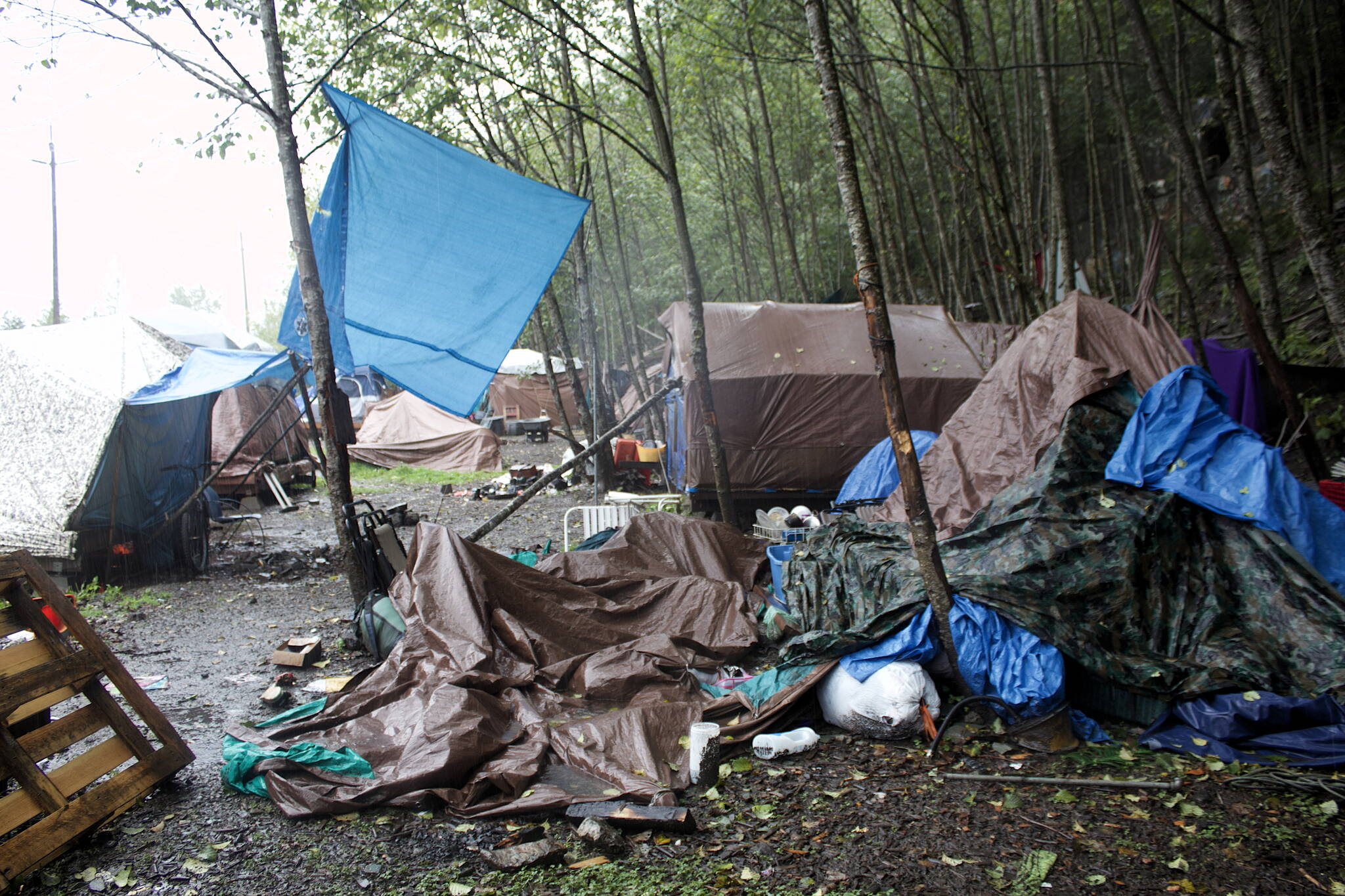 Trash, debris and abandoned belongings are strewn among occupied tents at the Mill Campground on the mountainside across from the cargo ship terminal in downtown Juneau on Monday. The campsite has been at or beyond full capacity through the summer, as have other facilities for the homeless, due to various problems including skyrocketing housing costs and lack of vacancies even for people able to pay at least some rent. (Mark Sabbatini / Juneau Empire)