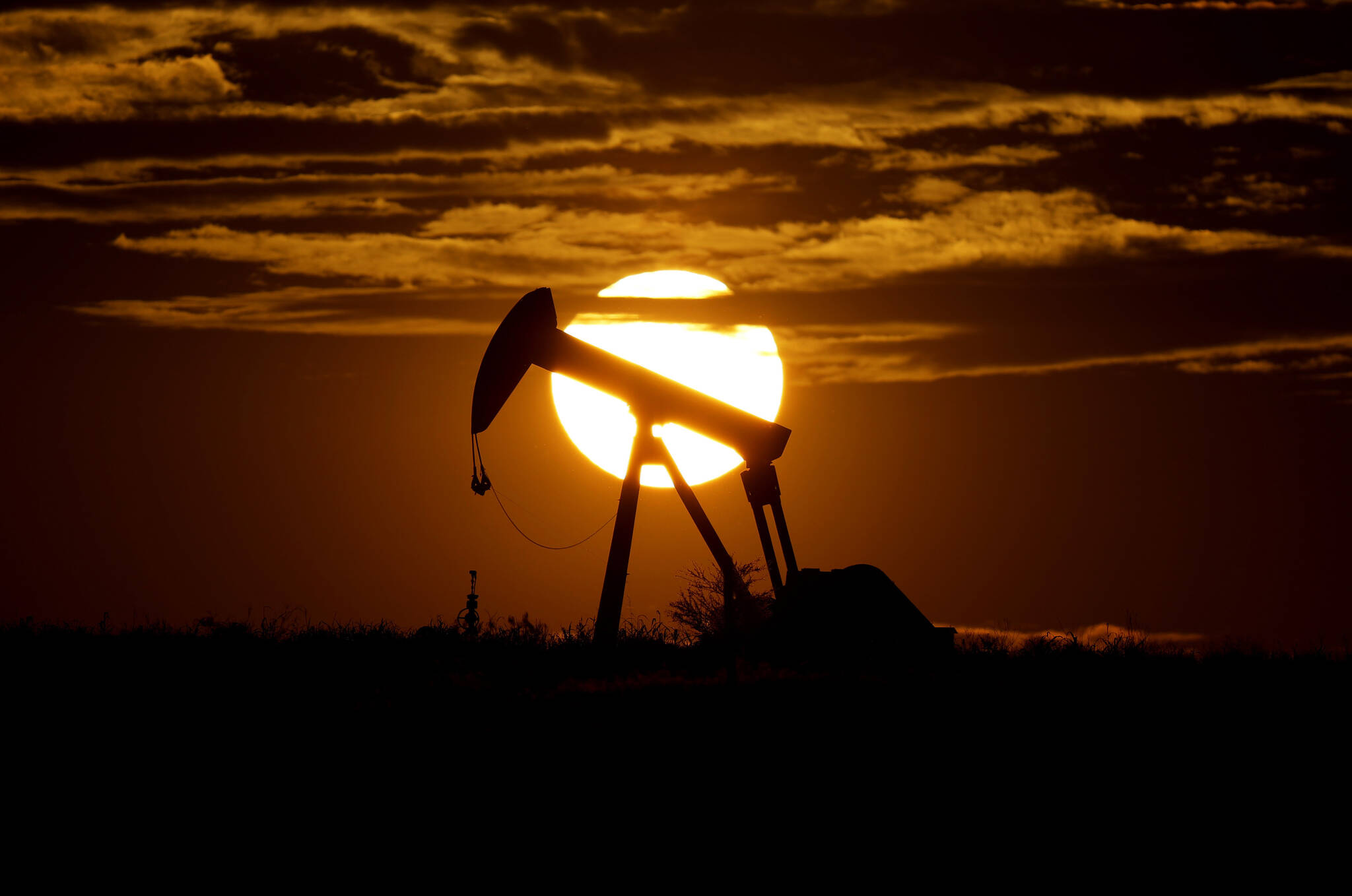 The sun sets behind an idle pump jack near Karnes City, USA, April 8, 2020. Oil prices are sagging amid fears of recessions across the globe. OPEC and allied countries are weighing what to do about that when they meet online Thursday, Sept. 8, 2022. High oil prices were a bonanza for countries like Saudi Arabia over the summer, but now they're well off those highs. Saudi Arabia's oil minister has even said the group known as OPEC+ could cut production at any time. (AP Photo / Eric Gay)
