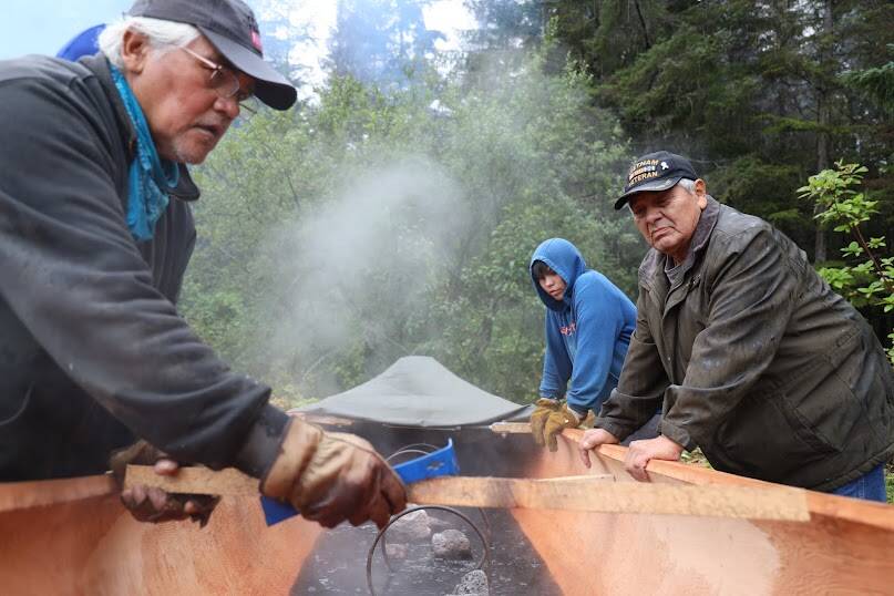 Tlingit master carver Wayne Price wedges a piece of wood between the width of the dugout canoe he and students at Chatham School District steamed on Tuesday. It’s the first dugout canoe to be made in Angoon since 1882 when the U.S. Navy bombarded the village, destroying all but one of its fleet of dugout canoes. (Clarise Larson / Juneau Empire)