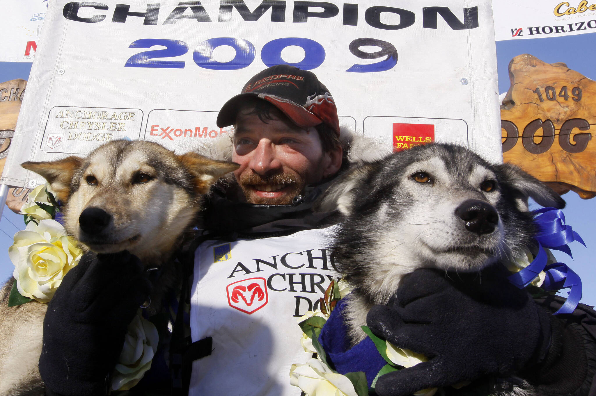 FILE - Lance Mackey sits with his lead dogs Larry, right, and Maple after crossing the finish line of the Iditarod Trail Sled Dog Race on March 18, 2009, in Nome, Alaska, to win his third Iditarod in a row. Mackey, a four-time Iditarod Trail Sled Dog Race winner and one of mushing’s most colorful and accomplished champions who also suffered from health and drug issues, died Wednesday, Sept. 7, 2022, his father and kennel announced on Facebook. He was 52. (AP Photo/Al Grillo, File)