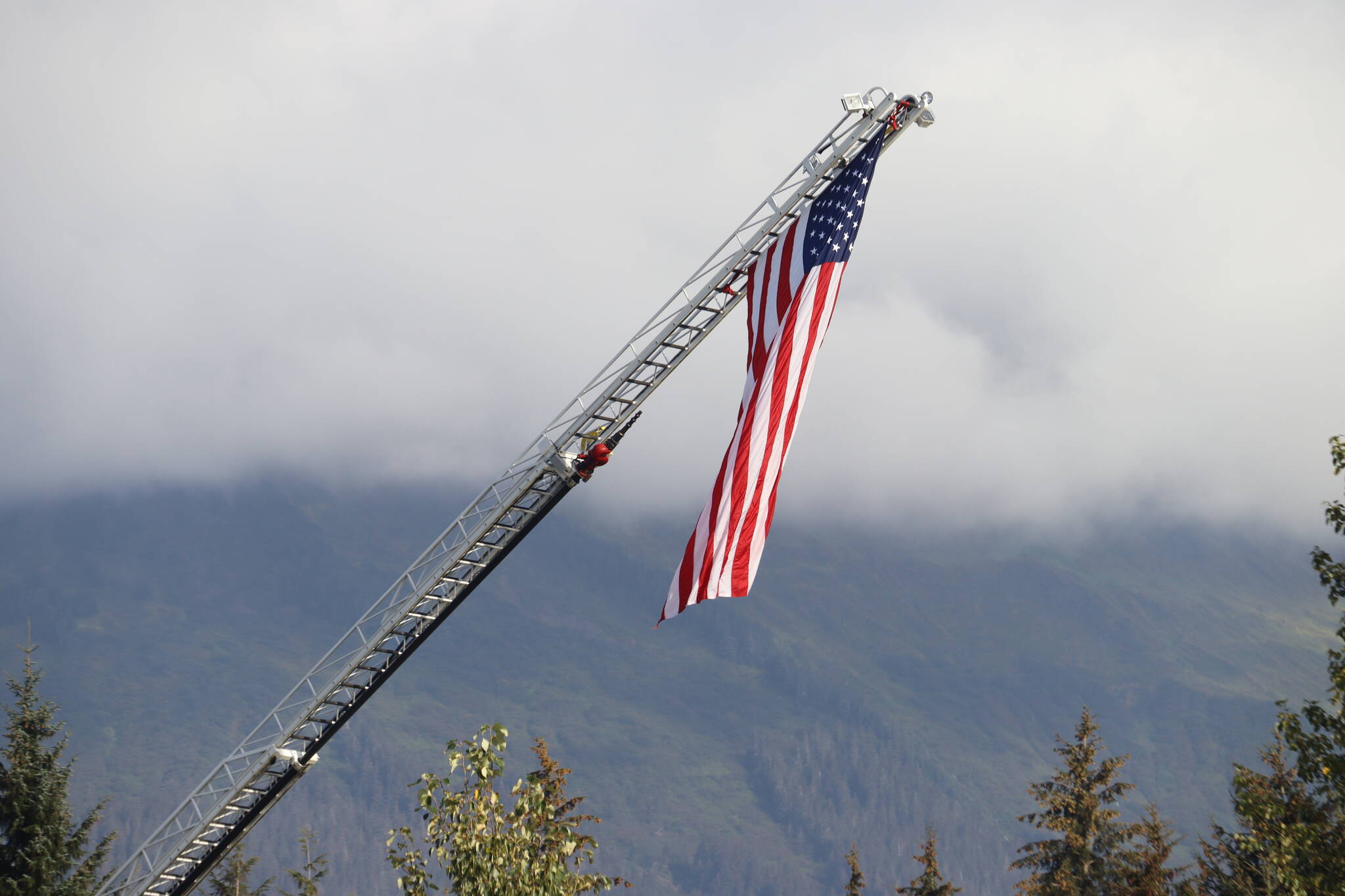 Capital City Fire and Rescue raised the flag during the rendition of “Amazing Grace,” performed by Scott Marnon of the City of Juneau Pipe Band. (Jonson Kuhn / Juneau Empire)