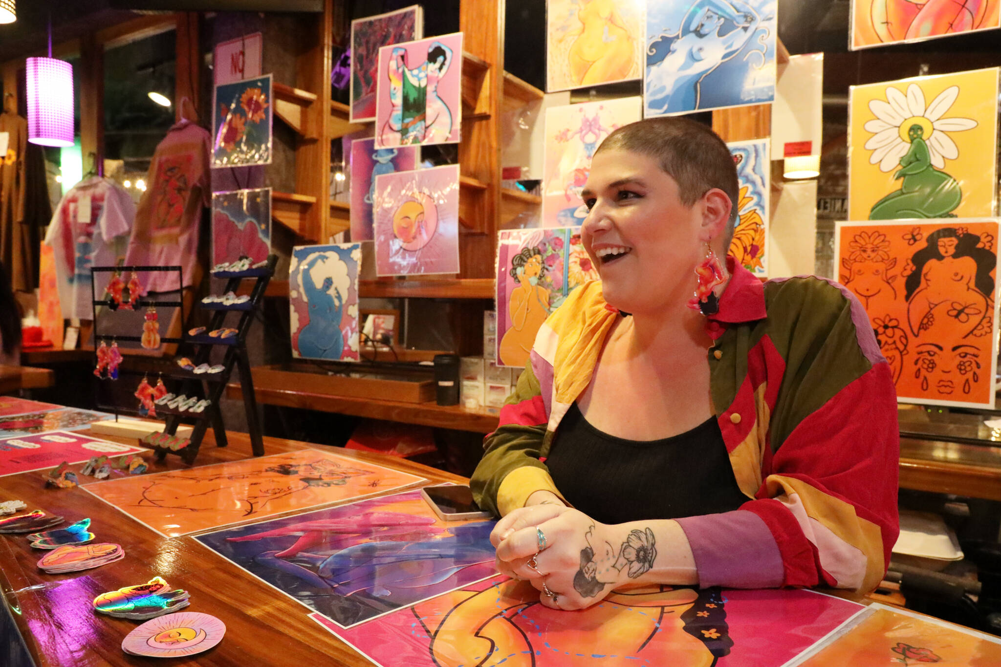 Natalie Weinberg smiles while talking with an attendee at the Crystal Saloon Thursday evening open mic and market a part of the BABEFEST series. Weinberg and other local artists lined the back portion of the saloon to feature and sell their work. (Clarise Larson / Juneau Empire)