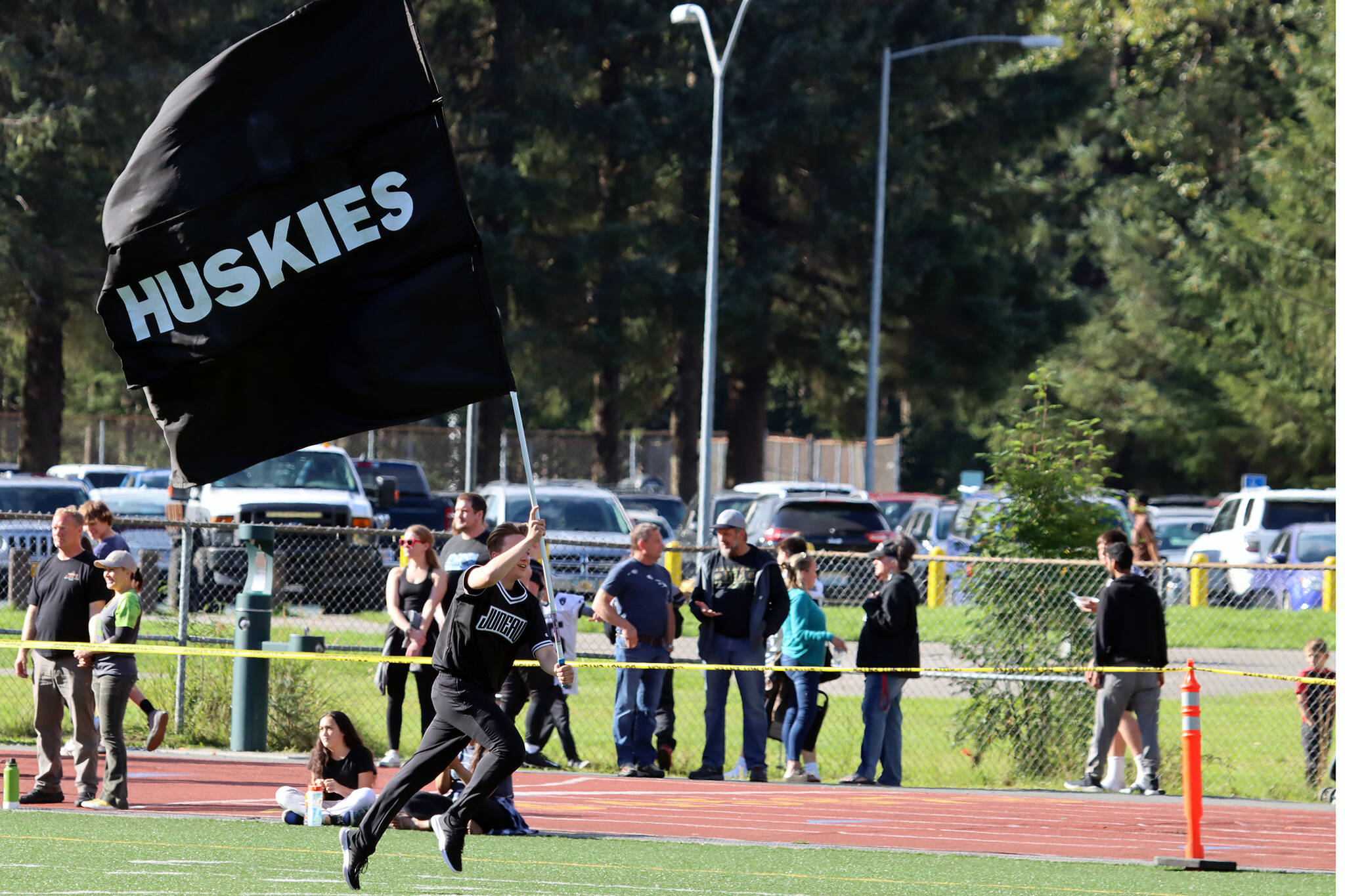 A student runs while holding a Juneau Huskies flag during a home game. Juneau will host Service High School for senior night on Saturday. Varsity is set for a 3 p.m. kickoff. Junior varsity plays at noon. (Ben Hohenstatt / Juneau Empire File)