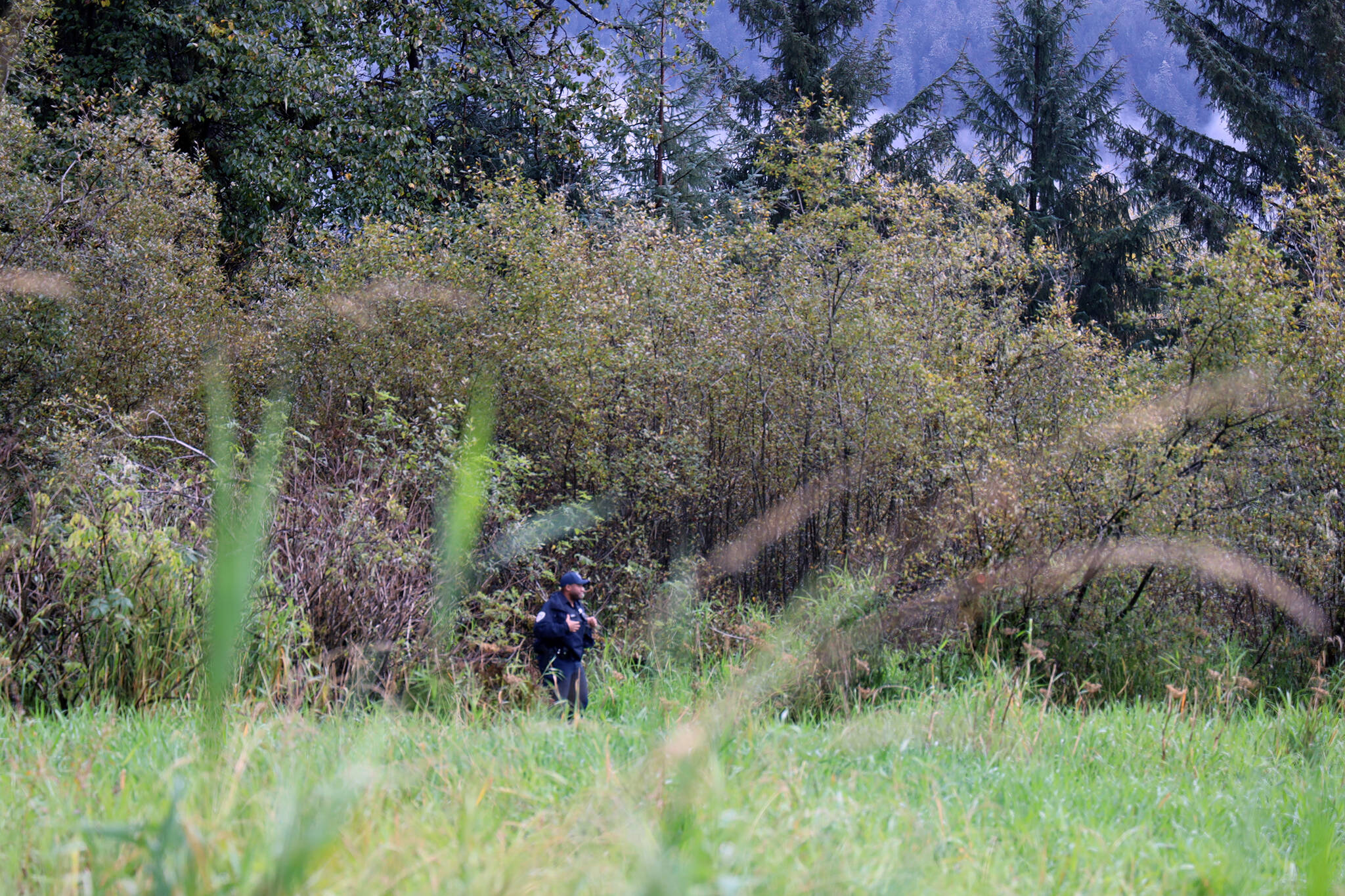 Clarise Larson / Juneau Empire
Officer Taylor Davis stands in a wooded area near what police described as an active crime scene. Davis and another officer asked for people to stay away from the area until further notice. No further details were offered from the officers as of 11 a.m.