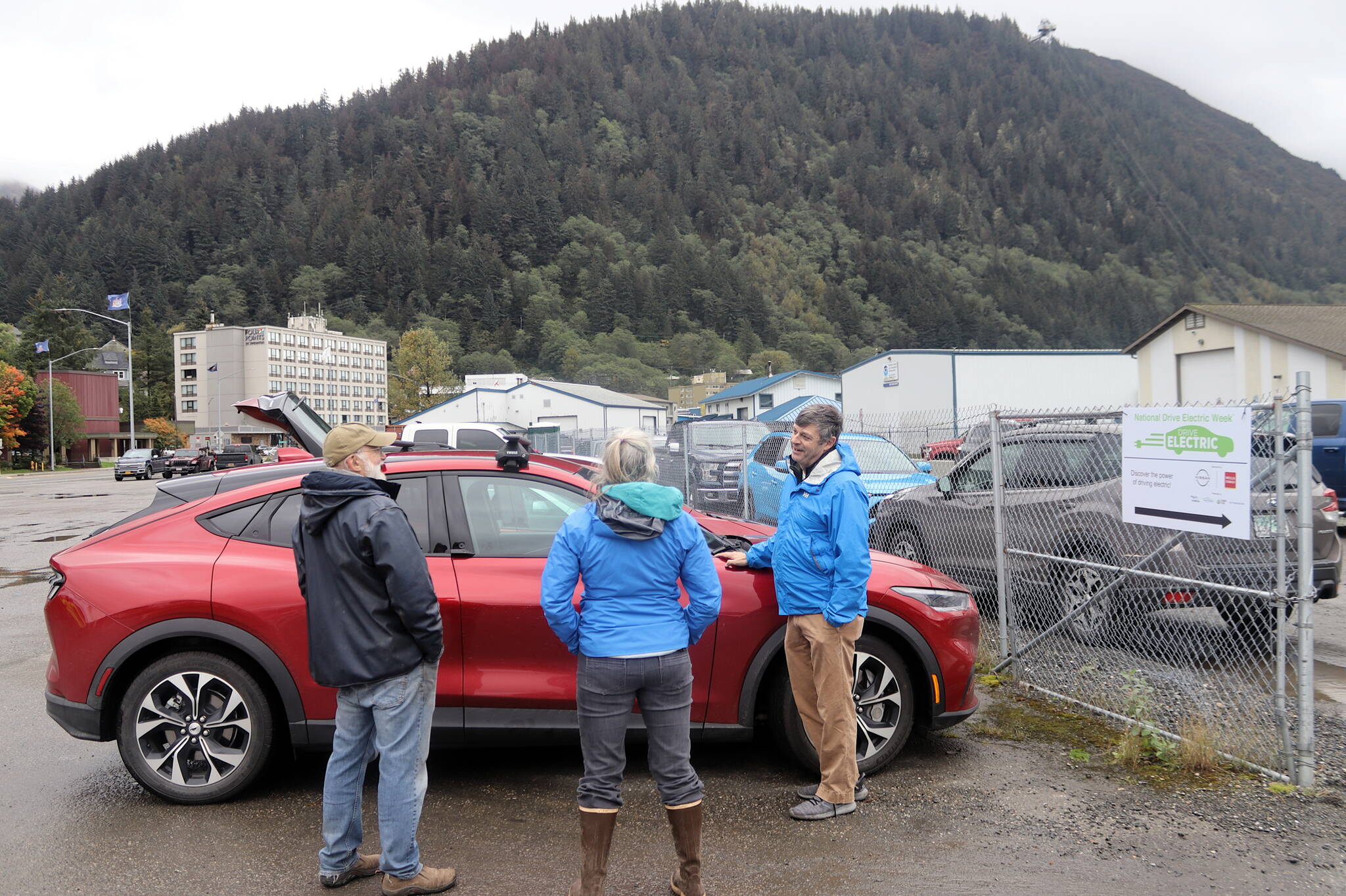 Jim Scheufelt, right, explains how his newly purchased Ford Mustang Mach-E operates to a couple of visitors at the ninth annual Juneau EV & EBIKE Roundup on Saturday. He said he has always driven Fords because his father worked for the company, but decided this year to make the switch from gas to electric. He said his wife drives a similar model and their son an electric Ford Focus, making them “an all-EV household.” (Mark Sabbatini / Juneau Empire)