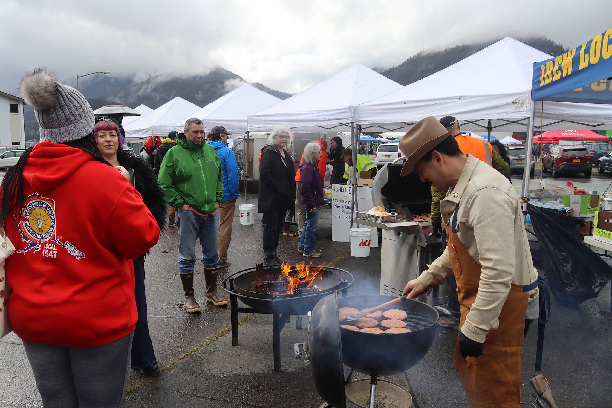 Rodney Hesson, assistant business manager of the local IBEW chapter, cooks burgers during the ninth annual Juneau EV & EBIKE Roundup on Saturday. He said he’s still driving a gas-powered truck because his wife is waiting for the debut of electric-powered VW Bus. (Mark Sabbatini)