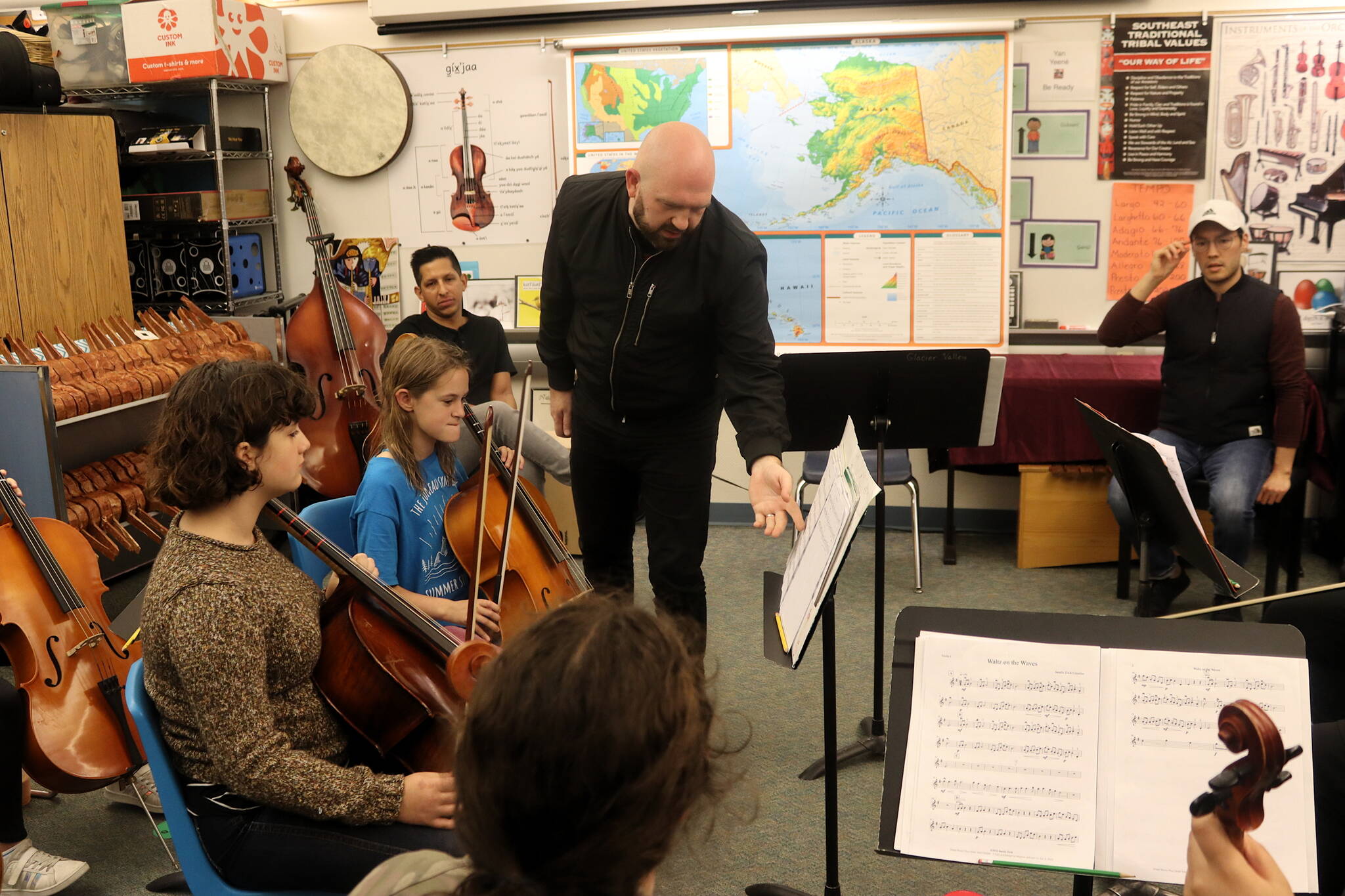 Zack Clark, right, of the visiting Simply Three string trio borrows a violin from Arlo Carlton, 12, to demonstrate a technique during a workshop Friday evening at Sitʼ Eeti Shaanáx̱ Glacier Valley Elementary School for a dozen students in grades 6-12 who are alumni of the Juneau Alaska Music Matters (JAMM) program. The students performed a 30-minute concert Saturday night at Juneau-Douglas High School: Yadaa.at Kalé before Simply Three took the stage to perform the finale of the fall Juneau Jazz Classics festival. (Mark Sabbatini / Juneau Empire)
Glen McDaniel, the cellist for Simply Three, explains a playing technique to students in the Juneau Alaska Music Matters (JAMM) program during a workshop Friday at Sitʼ Eeti Shaanáx̱ Glacier Valley Elementary School. (Mark Sabbatini / Juneau Empire)