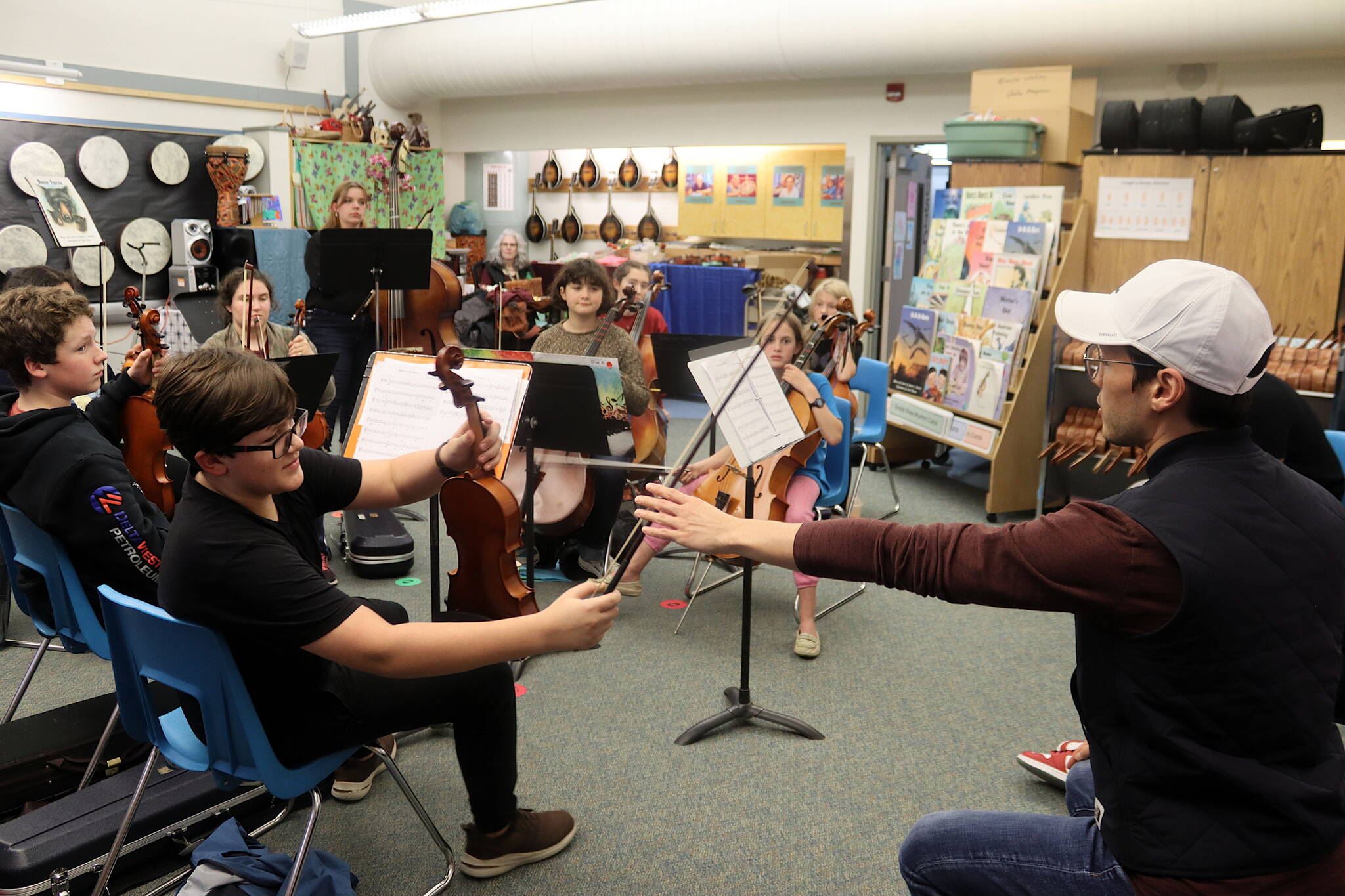 Zack Clark, right, of the visiting Simply Three string trio borrows a violin from Arlo Carlton, 12, to demonstrate a technique during a workshop Friday evening at Sitʼ Eeti Shaanáx̱ Glacier Valley Elementary School for a dozen students in grades 6-12 who are alumni of the Juneau Alaska Music Matters (JAMM) program. The students performed a 30-minute concert Saturday night at Juneau-Douglas High School: Yadaa.at Kalé before Simply Three took the stage to perform the finale of the fall Juneau Jazz & Classics festival. (Mark Sabbatini / Juneau Empire)