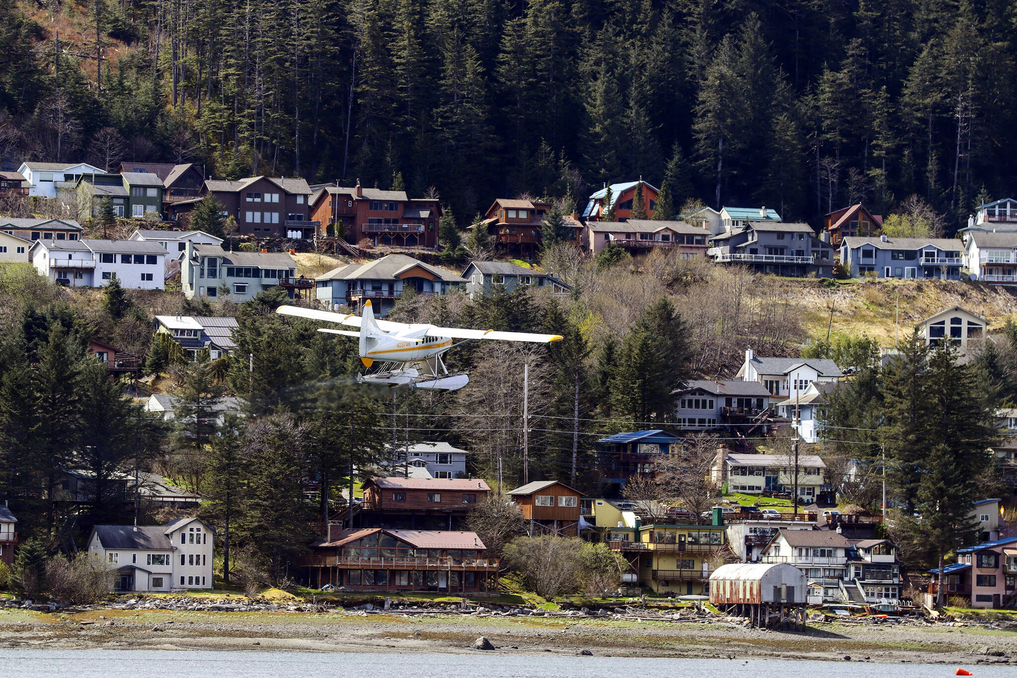 A plane flies in front of a downtown Juneau neighborhood in early May. City and Borough of Juneau Assembly Finance Committee members Wednesday discussed the availability of housing in Juneau. So far, Assembly members said, a tax abatement meant to spur development downtown has not been successful. (Michael S. Lockett / Juneau Empire File)