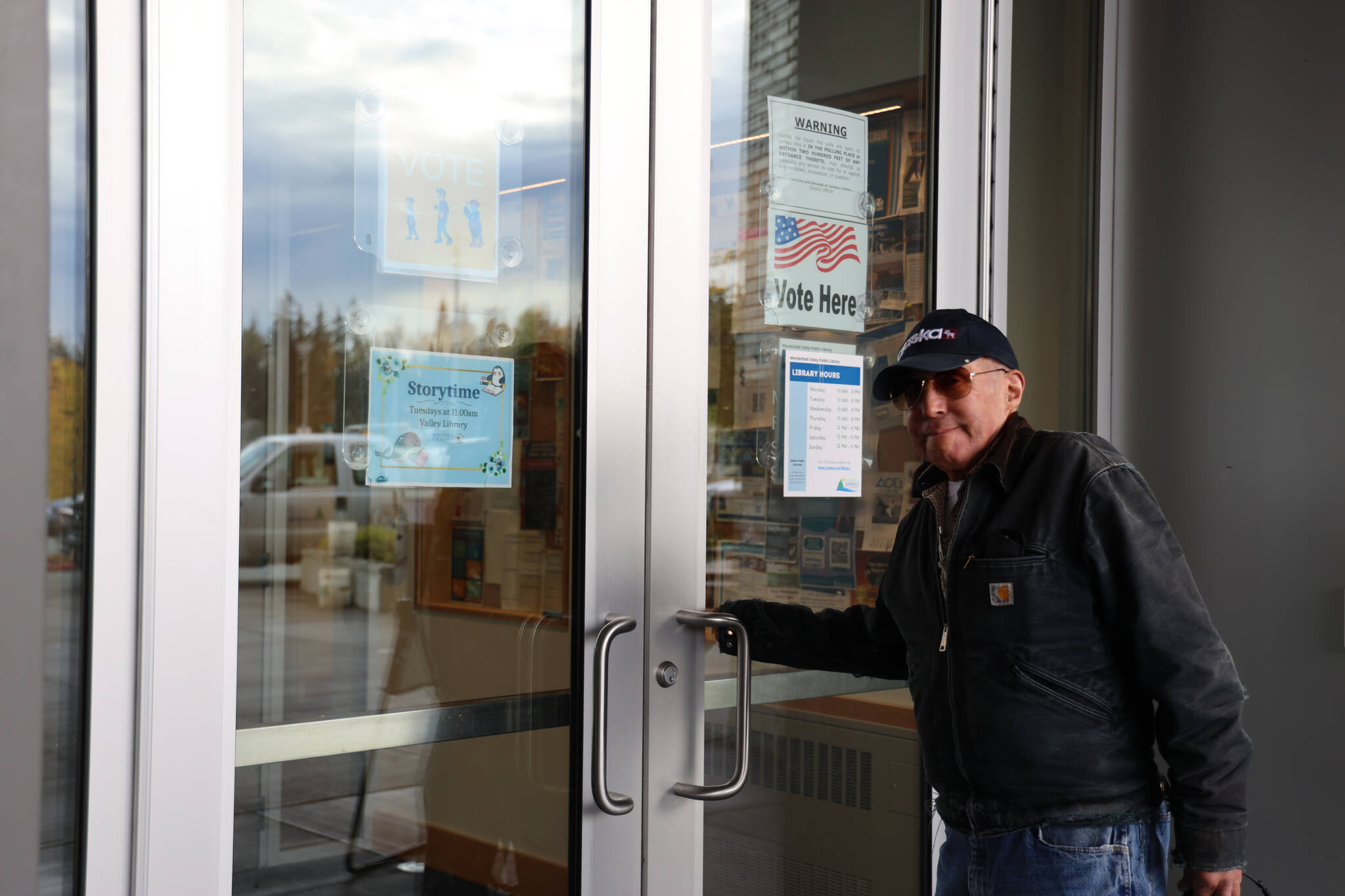 Larry Silverly opens the door at the voter center located at the Mendenhall Valley Public Library to cast his vote on Tuesday afternoon. (Clarise Larson / Juneau Empire)