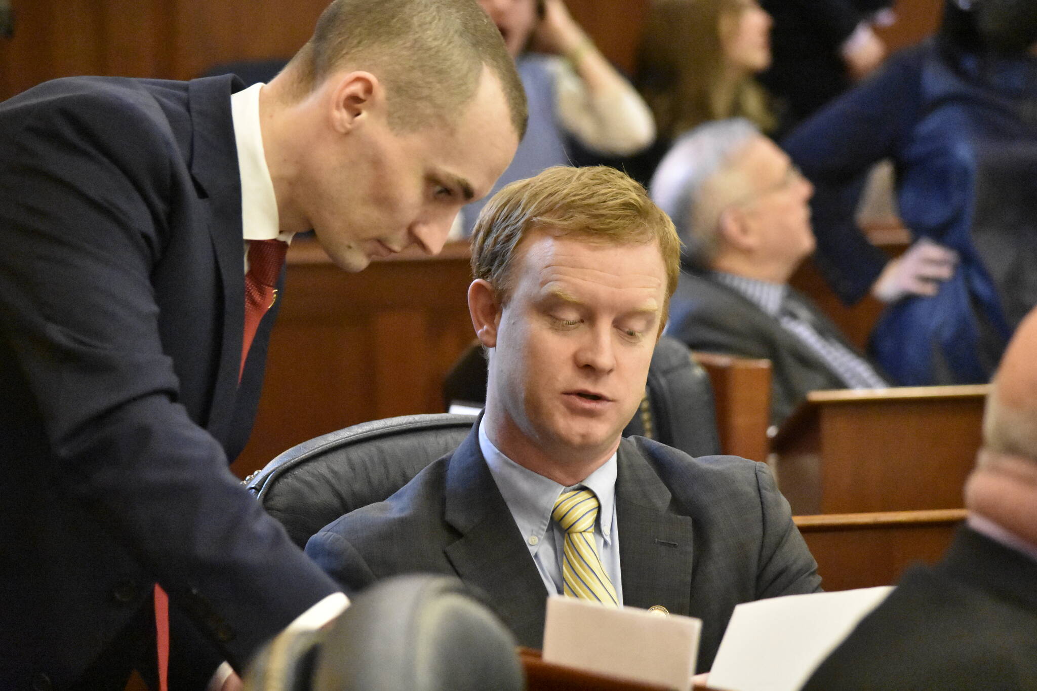 Reps. Clavin Schrage, I-Anchorage, left, and David Eastman, R-Wasilla, discuss a bill on the floor of the Alaska House of Representatives to enact limits on individual contributions to political campaigns, on Monday, March 14, 2022. (Peter Segall / Juneau Empire File)