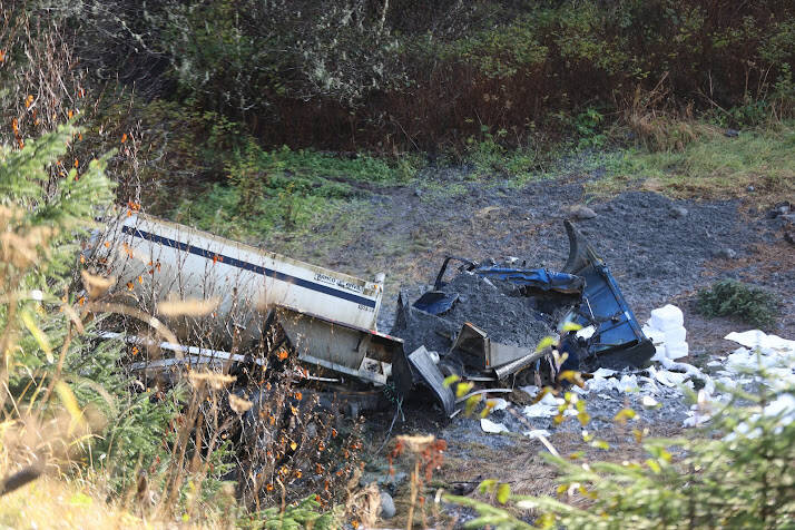 A dump truck lays mangled down an embankment below Glacier Highway near the Auke Bay Ferry Terminal Friday morning after crashing through the guardrail Thursday afternoon. (Clarise Larson / Juneau Empire)