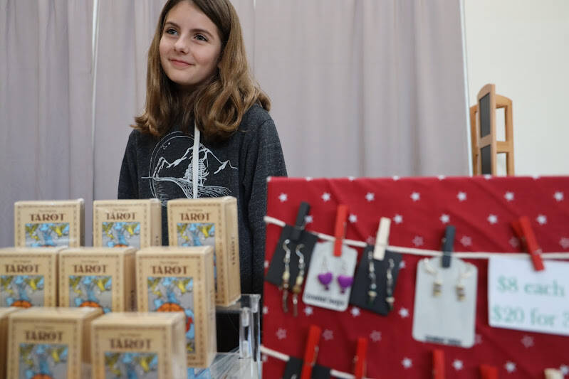Natalie Mackinnon, a business owner and sixth grade student at Dzantik’i Heeni Middle School, stands behind her booth featuring her handmade earrings at the Pumpkin Spice Market on Saturday. At just 11 years old Mackinnon started her own business, Goosebear Designs, last year and said she has been creating sets of earrings with her friends ever since. (Clarise Larson / Juneau Empire)