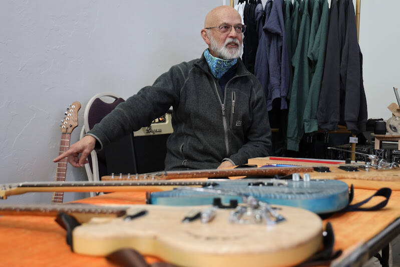 Juneau resident and retired teacher George Gress sits behind a table showing off a array of his many handmade guitars. Gress said after retiring in 2014 after 30 years of teaching, his wife gave him a small woodworking kit to try to introduce a small hobby for him, but it instead led him to create what is now his custom guitar business with products that have been sold worldwide. (Clarise Larson / Juneau Empire)