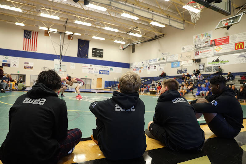 A group of Thunder Mountain High School wrestlers sit along the mat as they watch a match Saturday afternoon during the Brandon Pilot Invitational Wrestling Tournament at THMS. (Clarise Larson / Juneau Empire)