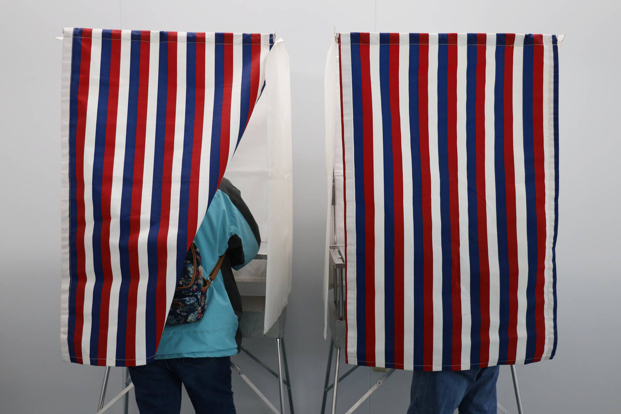 Two residents stand in voter booths Monday morning which marked the start for early and absentee in-person voting across the state for the Nov. 8 general election. (Clarise Larson / Juneau Empire)