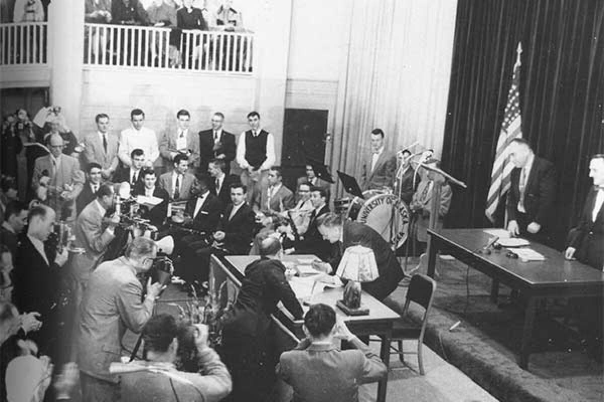 Bill Egan, president of the original Alaska constitutional convention and a future governor, signs the proposed Alaska Constitution in the gymnasium, now Signers’ Hall, on Feb. 5, 1956. (Photo courtesy of the University of Alaska Fairbanks)