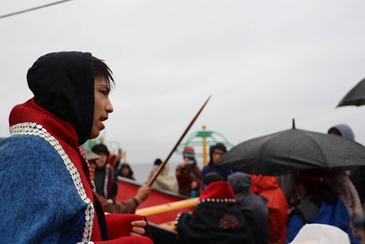 Kyle Johnson, a junior at Chatham School District, sings alongside residents as they walk down front street to commemorate 140 years since U.S. Navy bombarded the village, destroying all but one of its fleet of dugout canoes. (Clarise Larson / Juneau Empire)