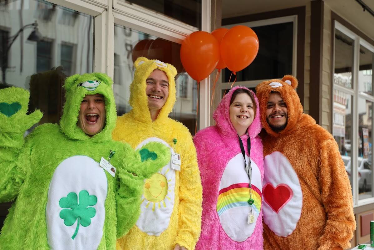 From left to right, Tressa Millam, Danny Ruesch, Marcus Brown, Jaime Ryan, smile in their matching Care Bears onesies. The group of SEARHC employees stood outside the Front Street Clinic Monday afternoon handing out candy, reflective safety gear and non-toxic chalk. (Clarise Larson / Juneau Empire)