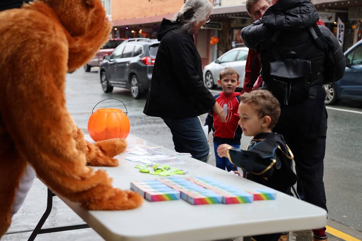 Children grab some candy at the table set up outside the SEARHC Front Street Clinic Monday afternoon. The downtown trick-or-treat tradition returned to the capital city with dozens of businesses opening their doors for trick-or-treaters young and old to snag a piece or two of candy while dressed in their finest costumes in celebration of Halloween. (Clarise Larson / Juneau Empire)