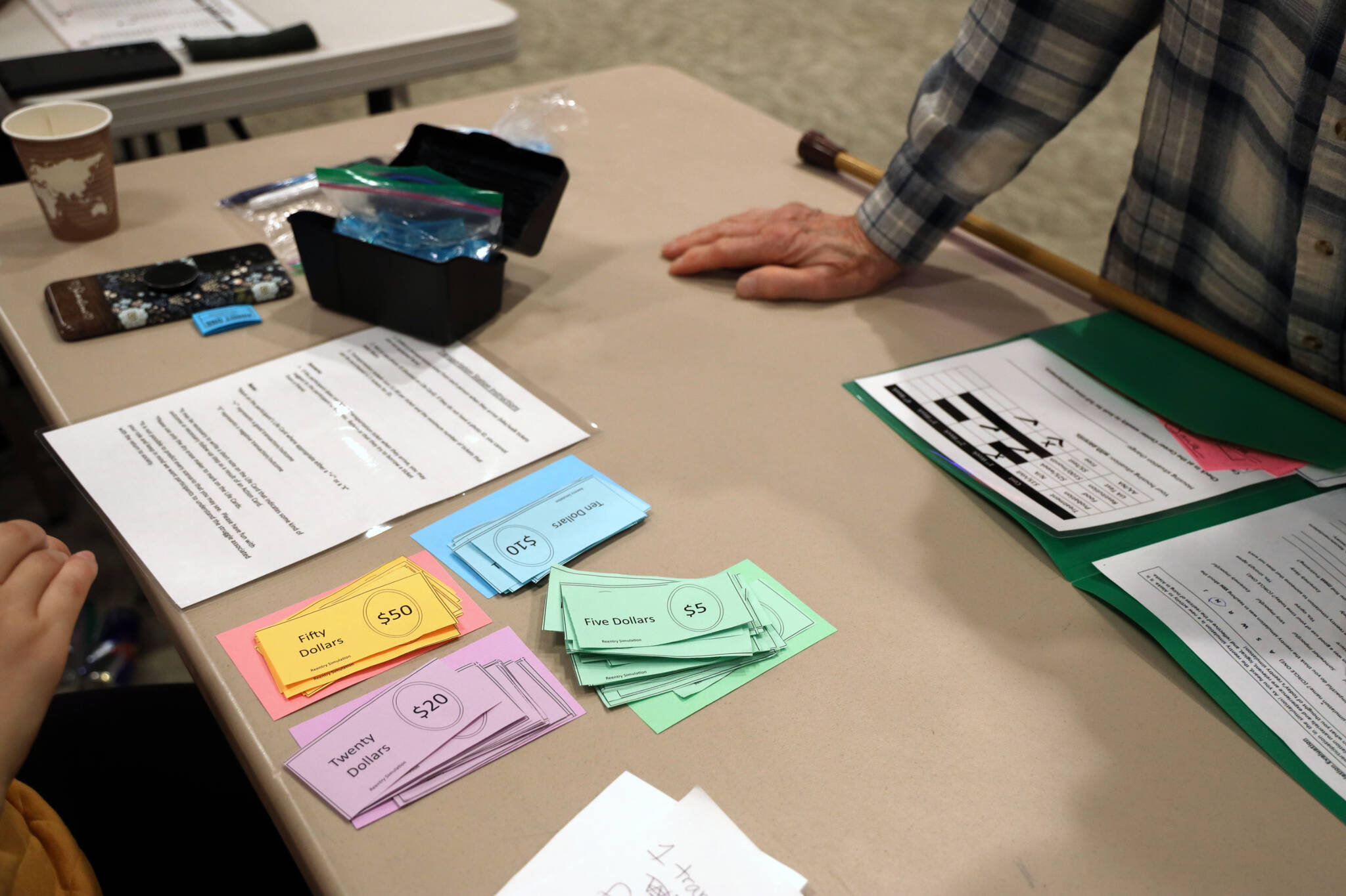 Fake money sits at one of the tables set up for people as a part of a reentry simulation at Elizabeth Peratrovich Hall hosted by the Juneau Reentry Coalition. (Clarise Larson / Juneau Empire)