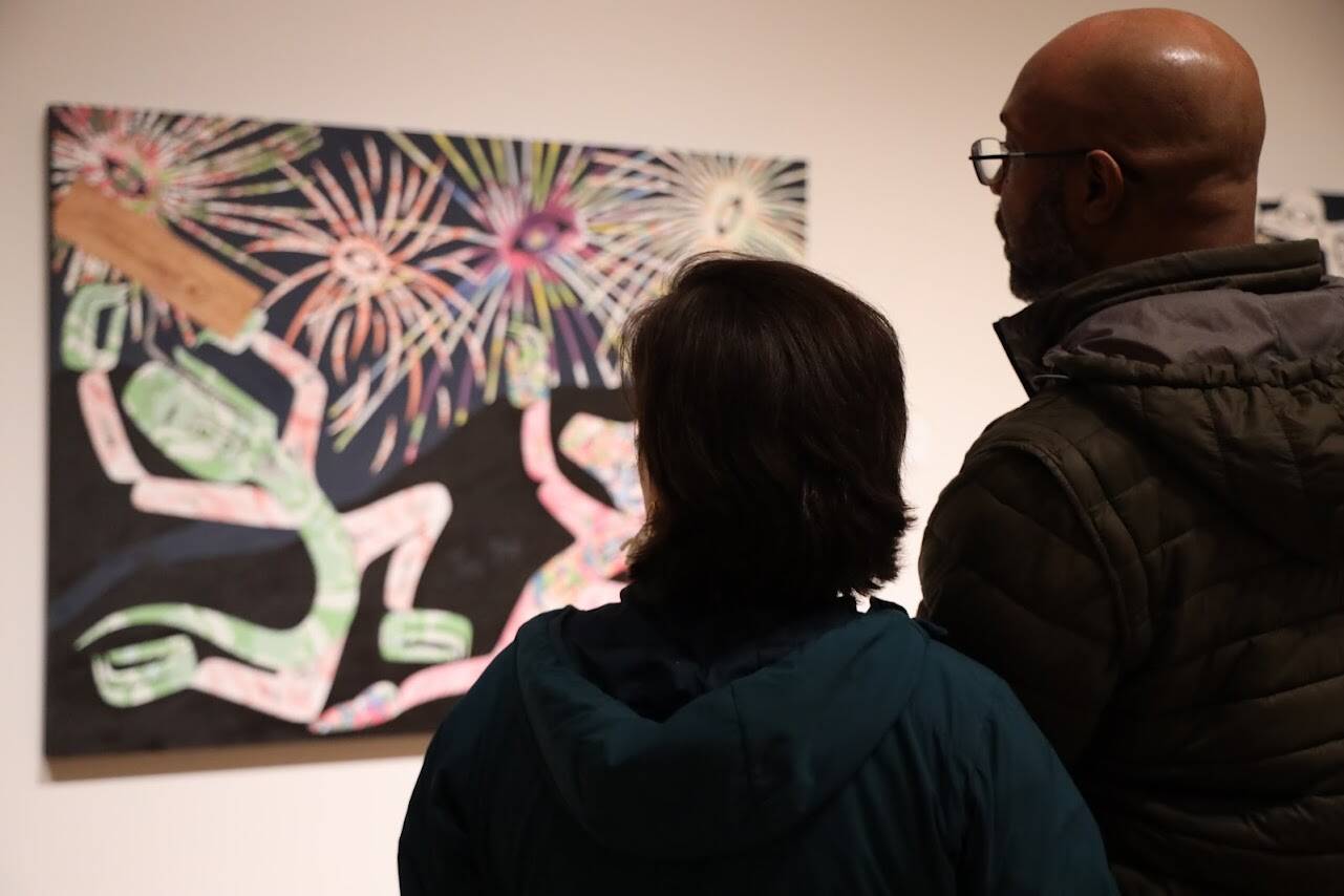A couple looks at Alison Bremner Nax̲shag̲eit’s piece “Midnight at the Fireworks Stand” featured in her solo exhibit on Friday evening at the Alaska State Museum. (Clarise Larson / Juneau Empire)
