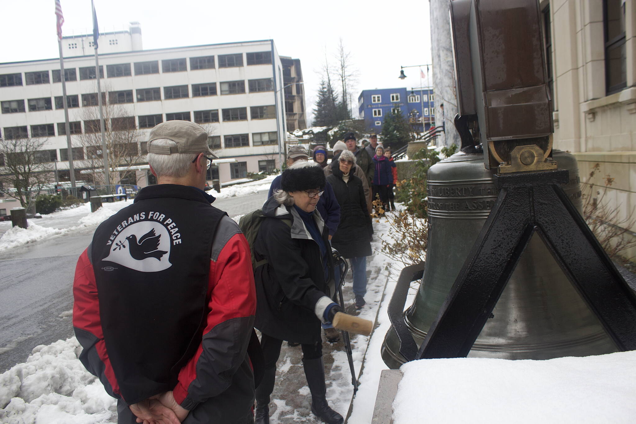 Juneau Veterans for Peace President Craig Wilson, left, watches a procession of fellow veterans and others ring the Liberty Bell replica in front of the Alaska State Capitol on Friday morning during an annual Armistice Day observation. (Mark Sabbatini / Juneau Empire)