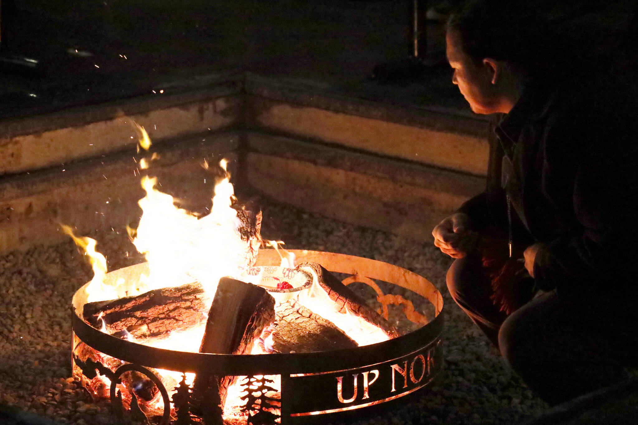 Clarise Larson / Juneau Empire 
X̱’unei Lance Twitchell sits next to a fire at a celebration of life ceremony hosted at the University of Southeast Alaska’s Noyes Pavilion in honor of late UAS professor Sol Neely Saturday evening.