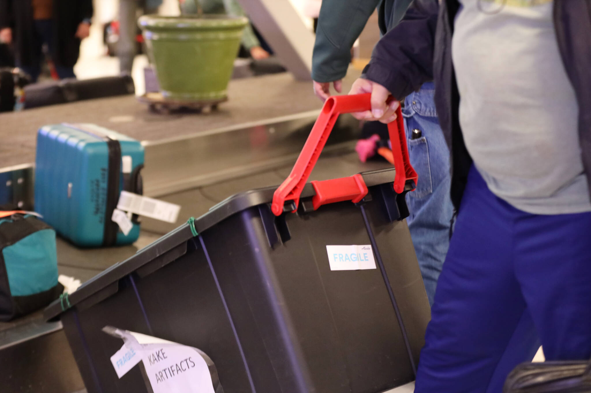 Frank Hughes pulls a tote filled with Alaska Native artifacts off the baggage carousel at the Juneau International Airport Thursday afternoon. (Clarise Larson / Juneau Empire)