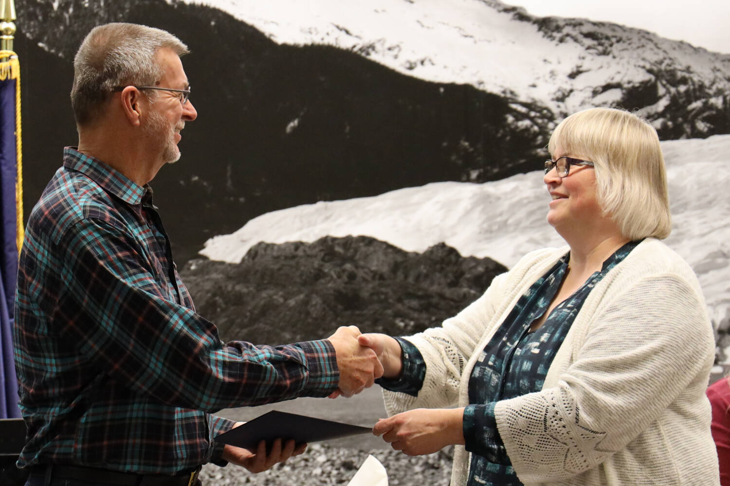 Kirby Day shakes hands with City and Borough of Juneau Mayor Beth Weldon at the Monday night Assembly meeting. Day was awarded a special recognition for his work administrating the city’s Tourism Best Management Practices program. (Clarise Larson / Juneau Empire)