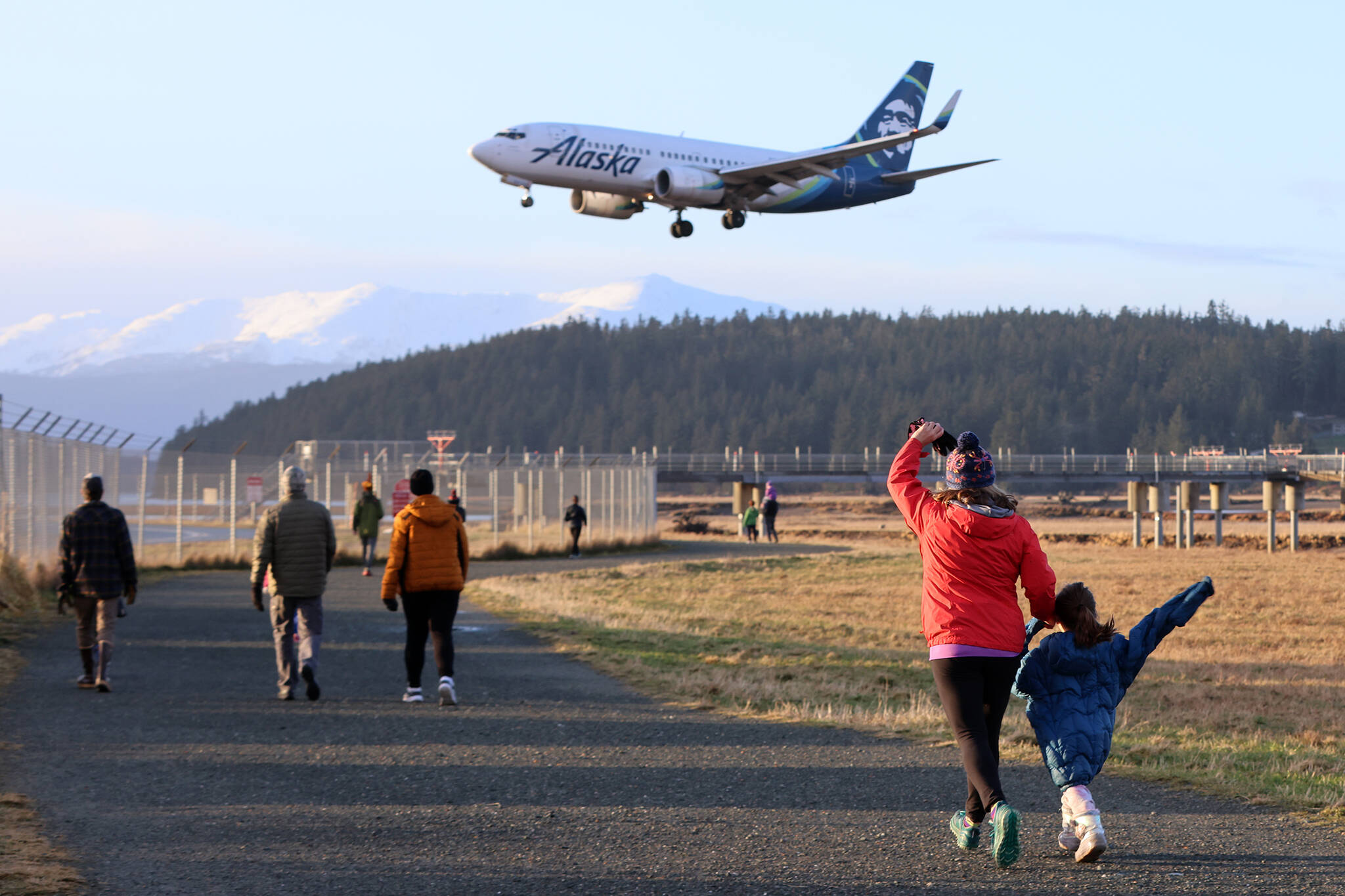 Turkey Trot participants wave at an Alaska Airlines plane landing at Juneau International Airport on Thanksgiving Day. (Ben Hohenstatt / Juneau Empire)