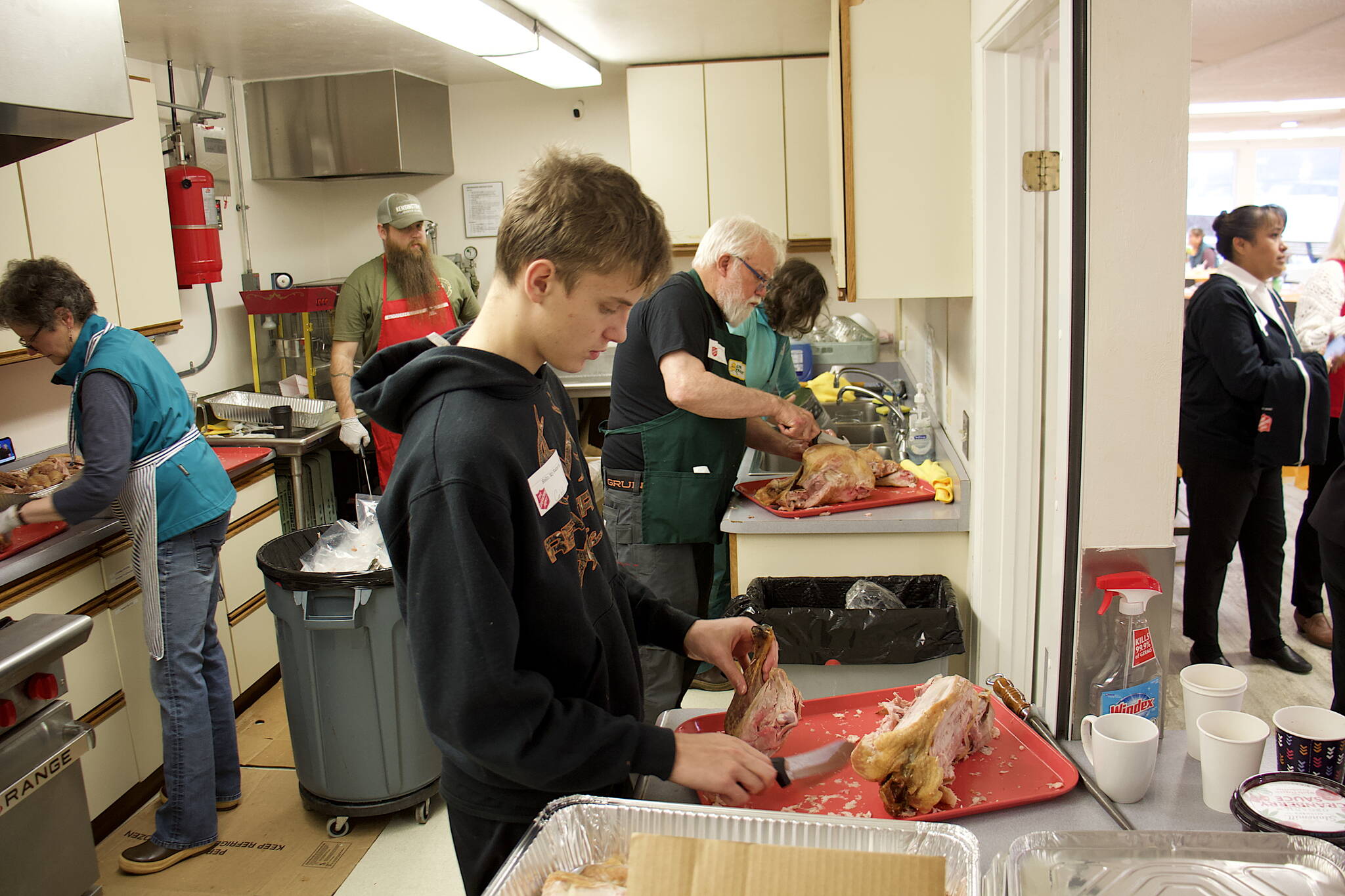 Caleb Friend, 16, and his grandfather, Jerry Harmon, carve turkeys in the kitchen of the Juneau Yacht Club before the serving of the annual communal Thanksgiving dinner at the Juneau Yacht Club. Friend, one of nine members of Harmon’s family volunteering during the day, said he has been helping since he started wrapping silverware at the age of six. Fifty turkeys were smoked for the gathering by Dick Hand, owner of Alaska Seafood Company. (Mark Sabbatini / Juneau Empire)