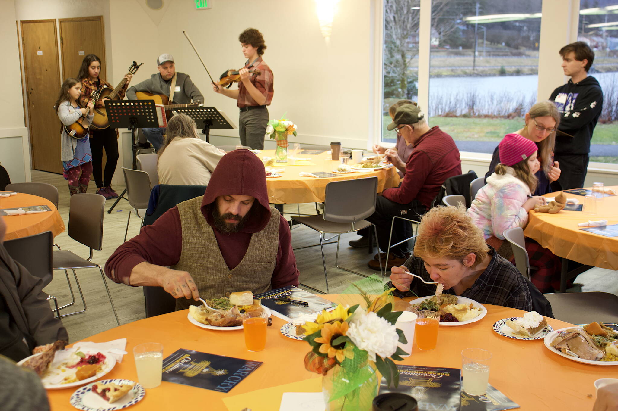 Garrett Derr and Valerie Parkinson eat Thanksgiving Dinner while the Koski Family Band plays folk music in the background at midday Thursday at the Juneau Yacht Club. Both are staying at The Glory Hall, which provided transportation for its residents to and from the annual meal hosted by The Salvation Army. (Mark Sabbatini / Juneau Empire)